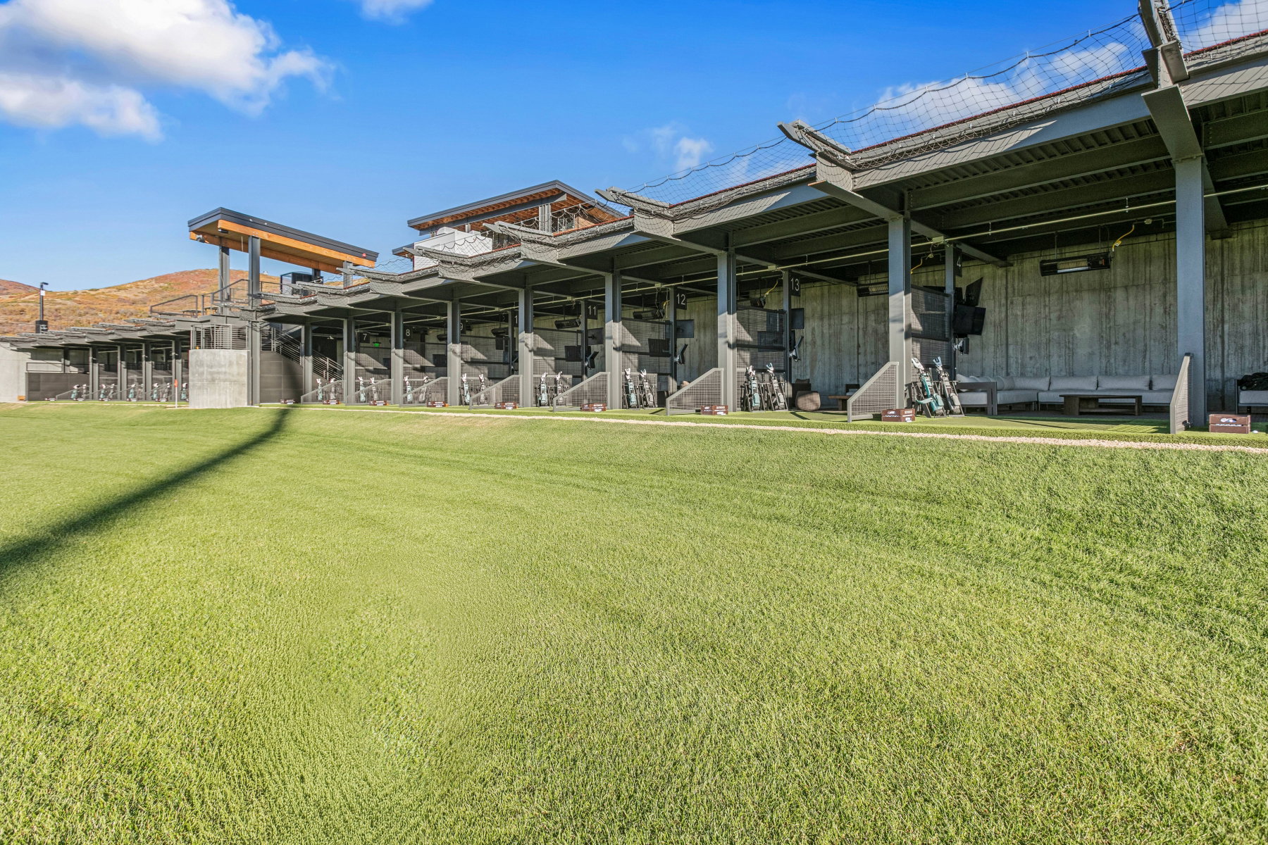 Expansive green turf with a multi-bay covered driving range structure