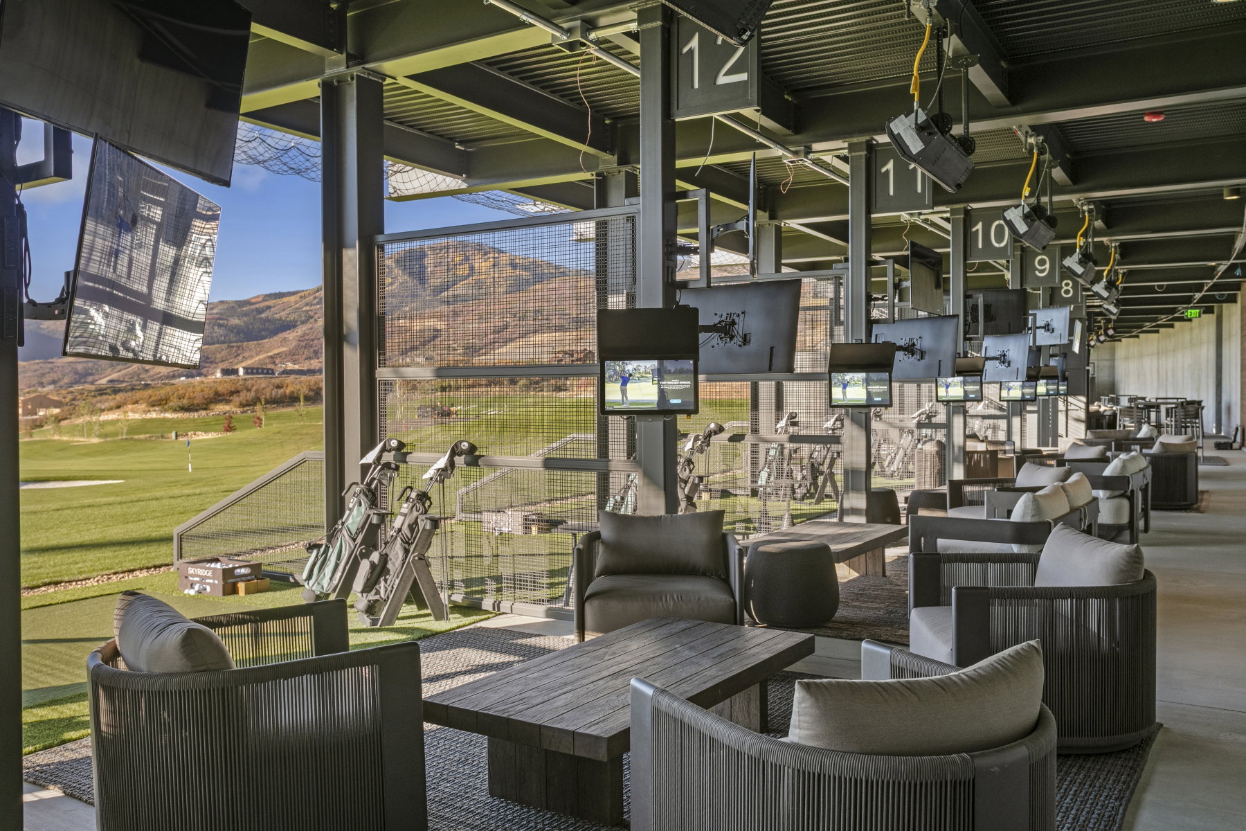 Covered outdoor recreation area with multiple bays, each featuring mounted monitors and a seating area