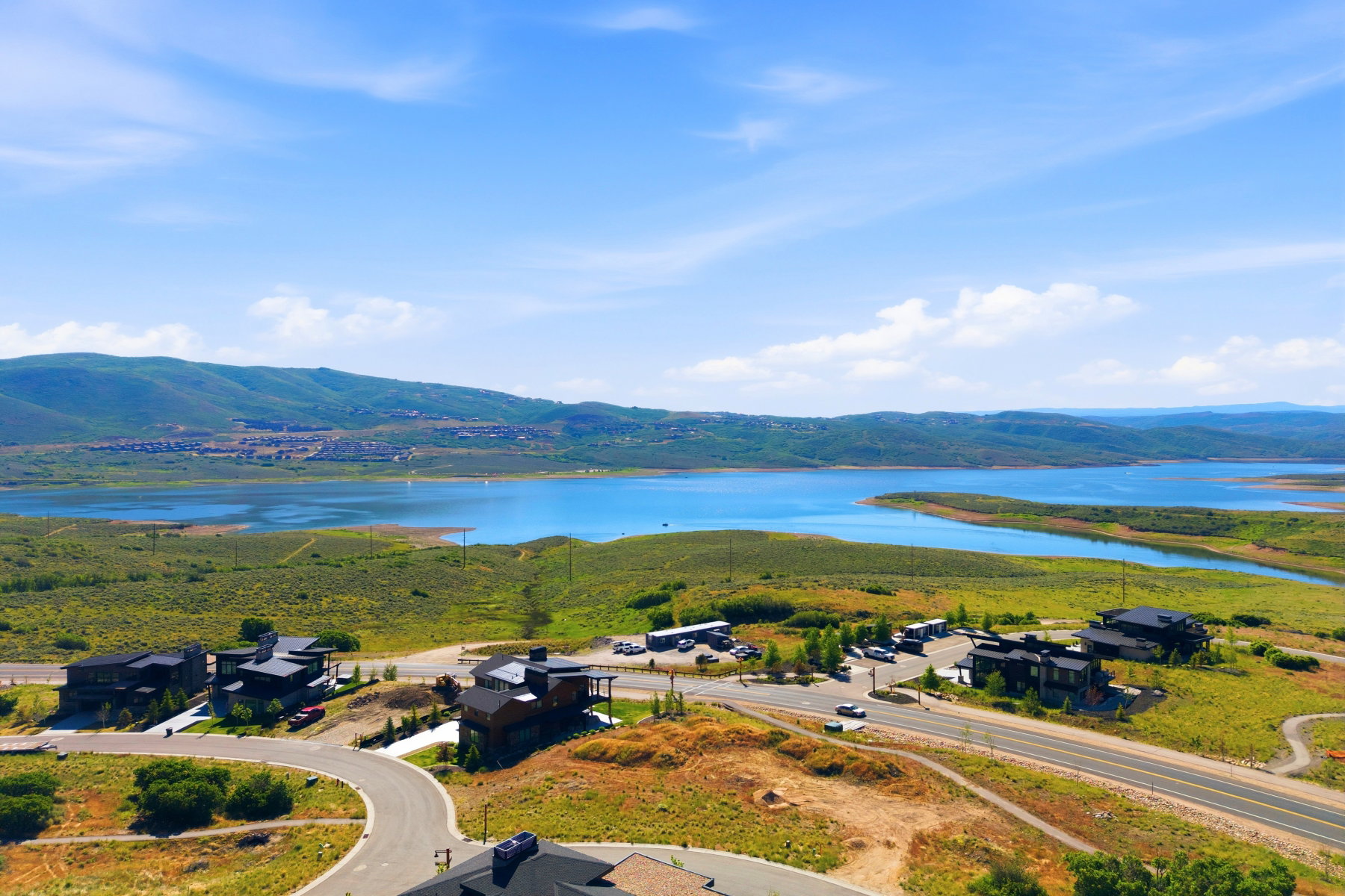 Expansive lakefront properties featuring modern architecture, surrounded by green landscape and distant mountains