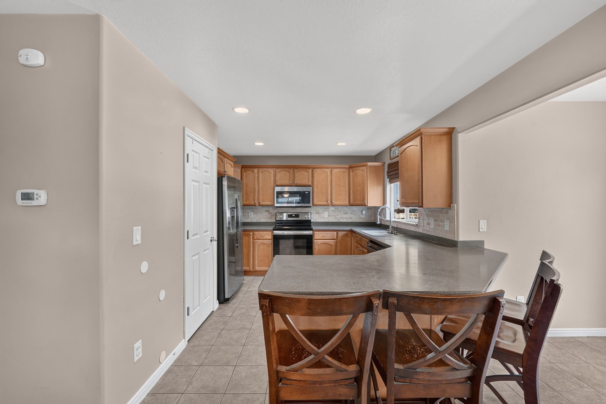 Kitchen featuring a U-shaped countertop with a breakfast bar, recessed lighting, tile flooring, and light wood-finish cabinetry