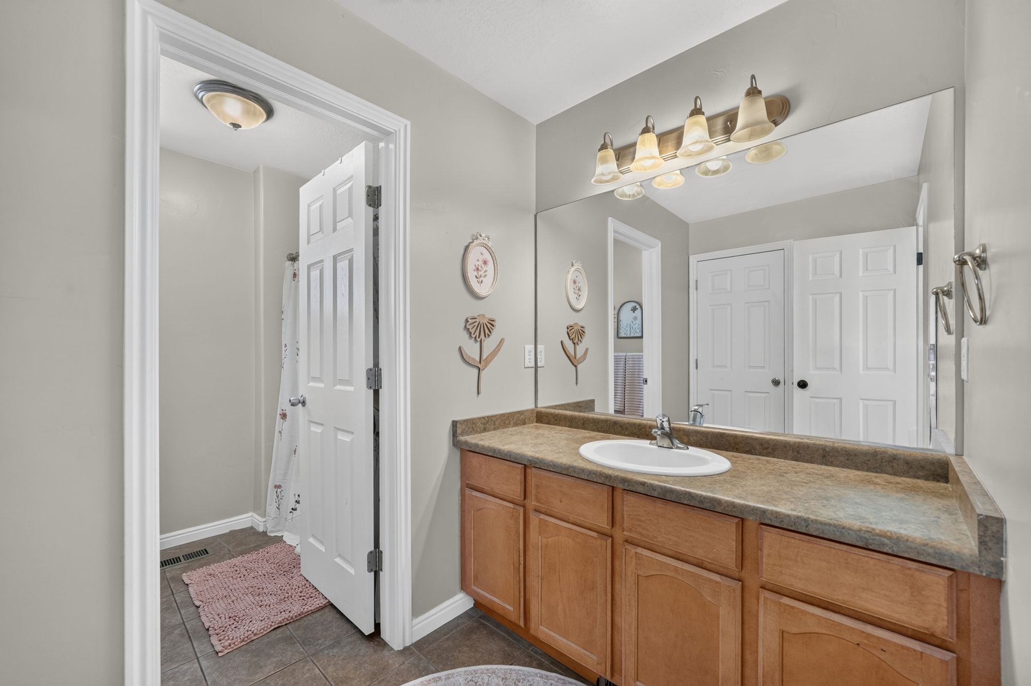 Bathroom vanity featuring a single basin sink, large mirror, and wood-finish cabinetry
