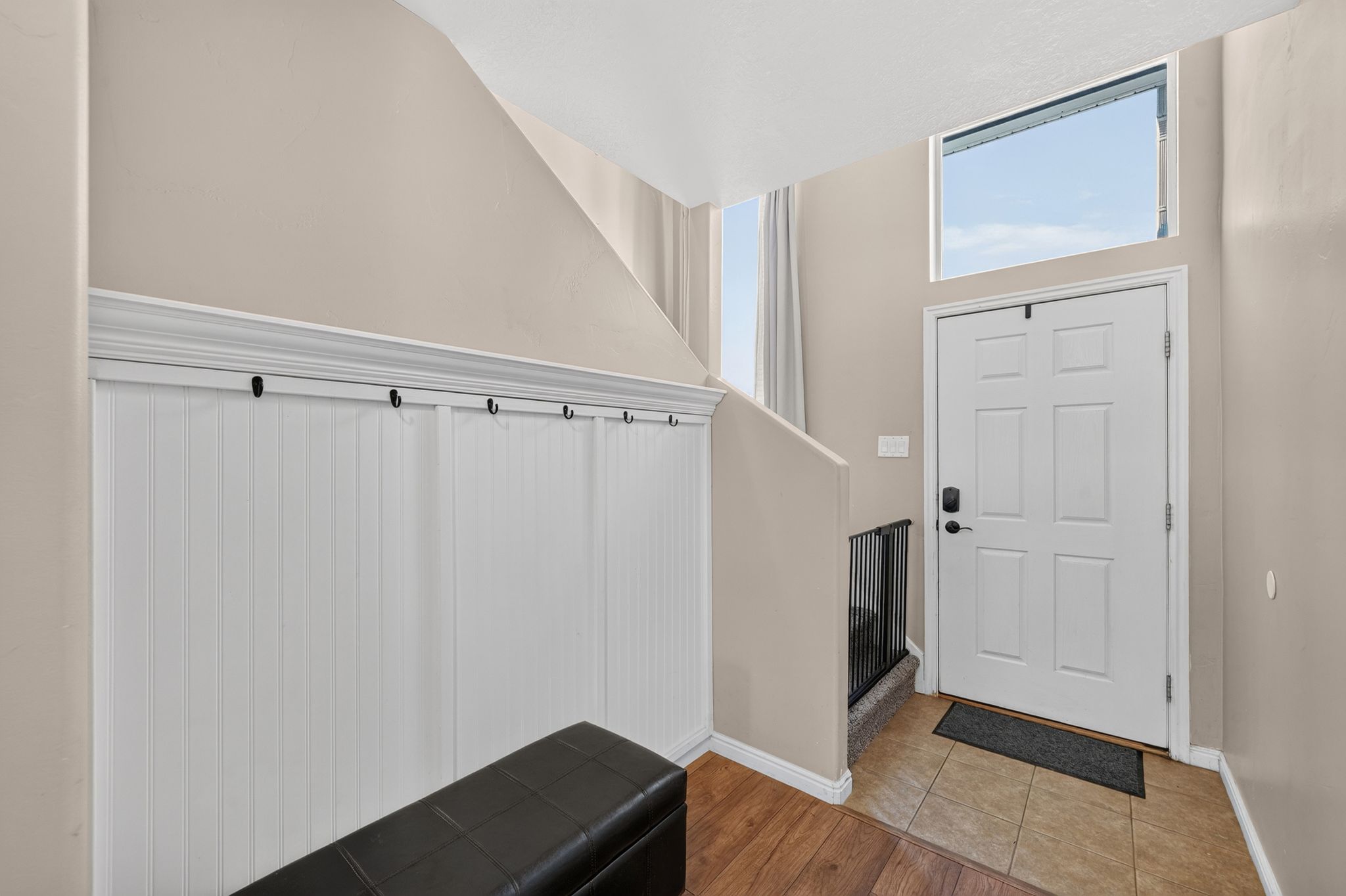 Entryway featuring a white paneled door with transom window, tile flooring, and wood-finish flooring