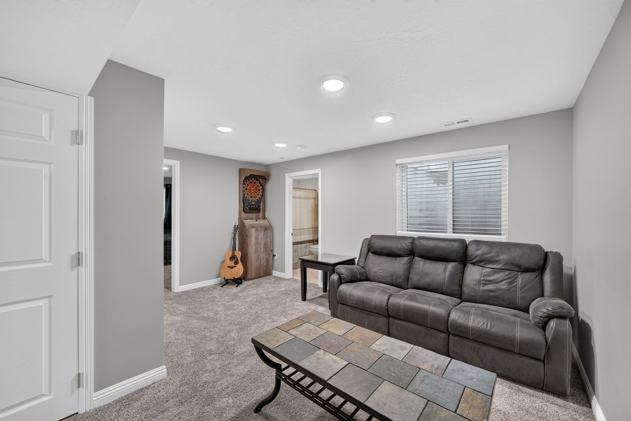 Carpeted living space featuring recessed lighting, a window with blinds, and white trim