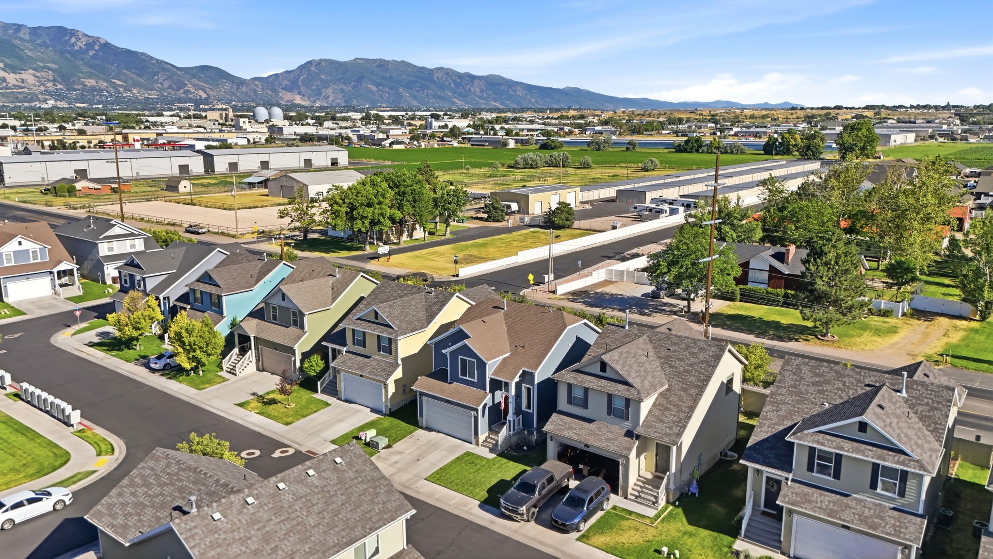 Residential development featuring individual homes with attached garages, manicured lawns, and varied exterior siding