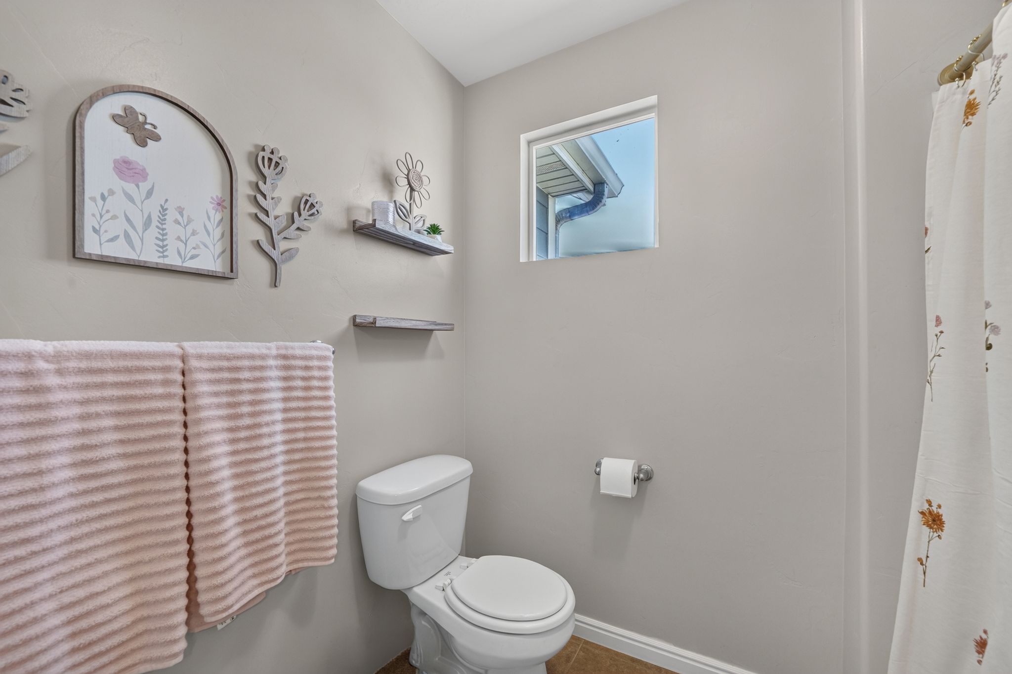 Bathroom featuring a white toilet, neutral wall paint, and a window with white trim