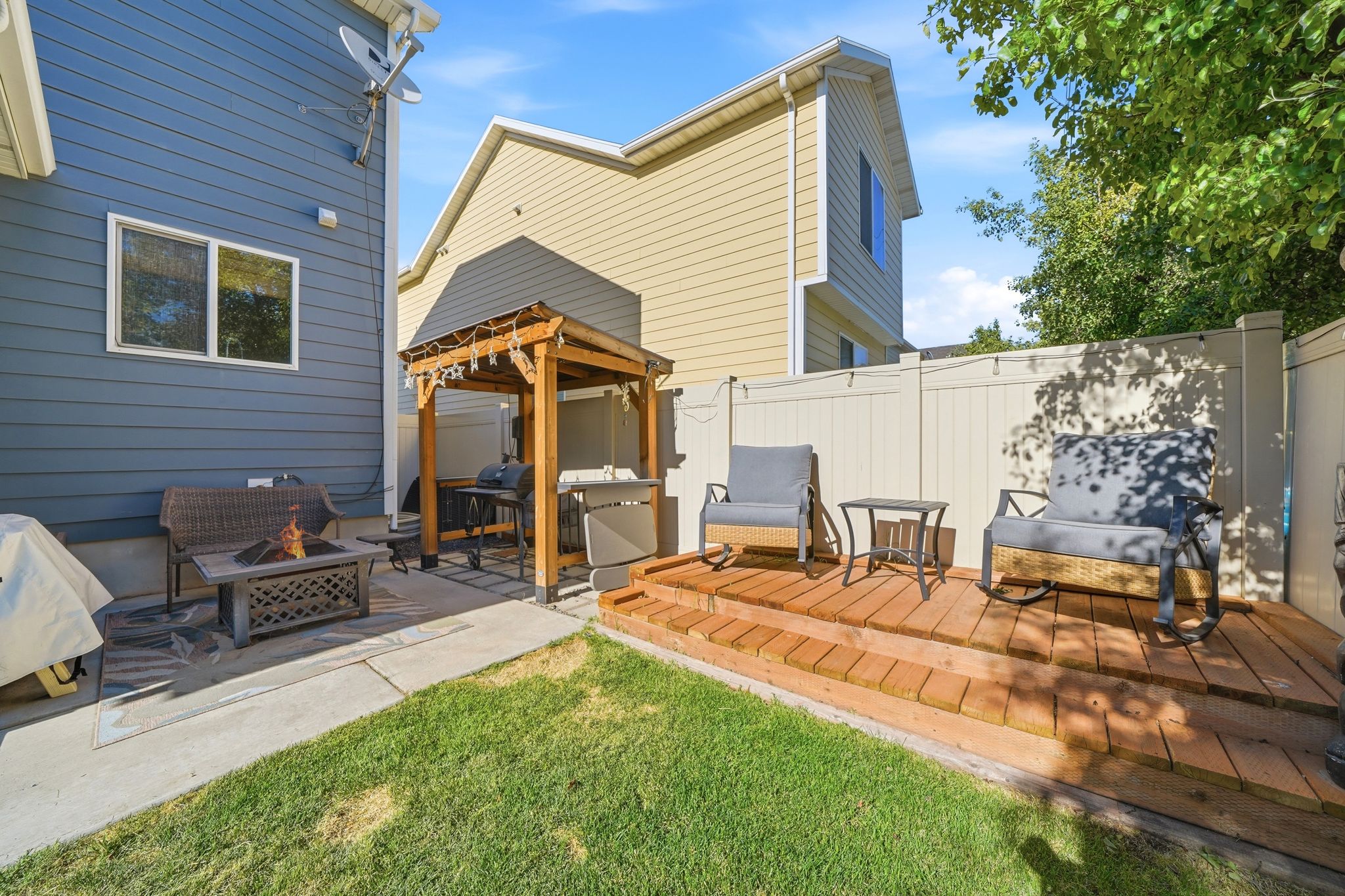Private backyard space featuring a tiered wood deck and concrete patio areas