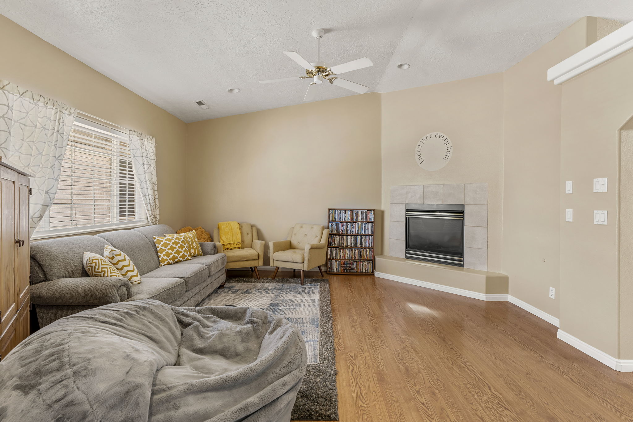 Spacious living area featuring a corner fireplace with a tiled surround, wood-finish flooring, vaulted ceilings, and recessed lighting