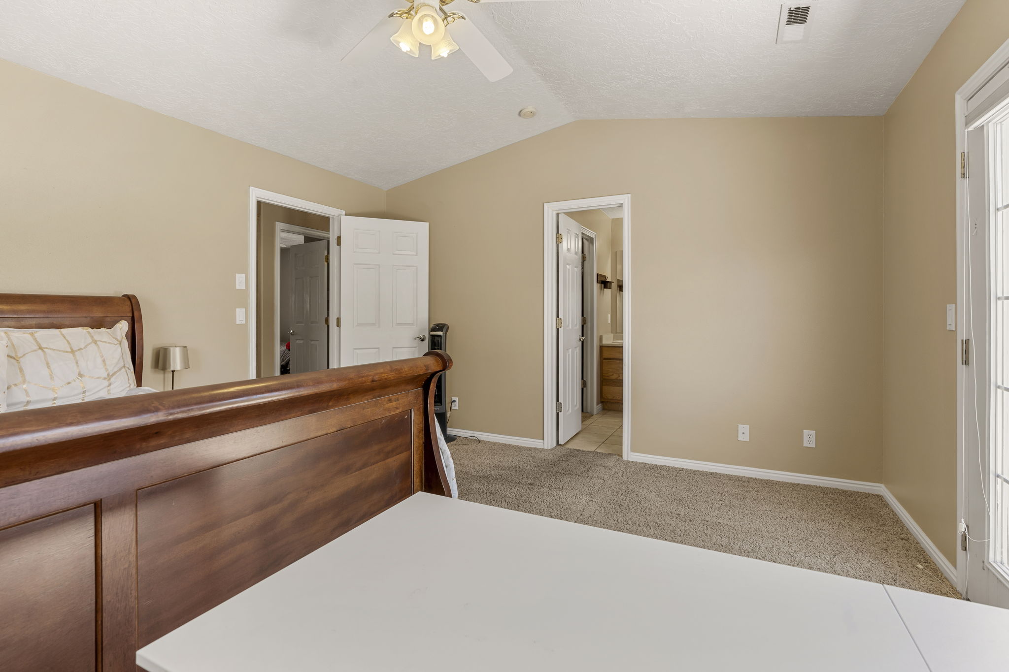 Carpeted room with vaulted ceiling and ceiling fan