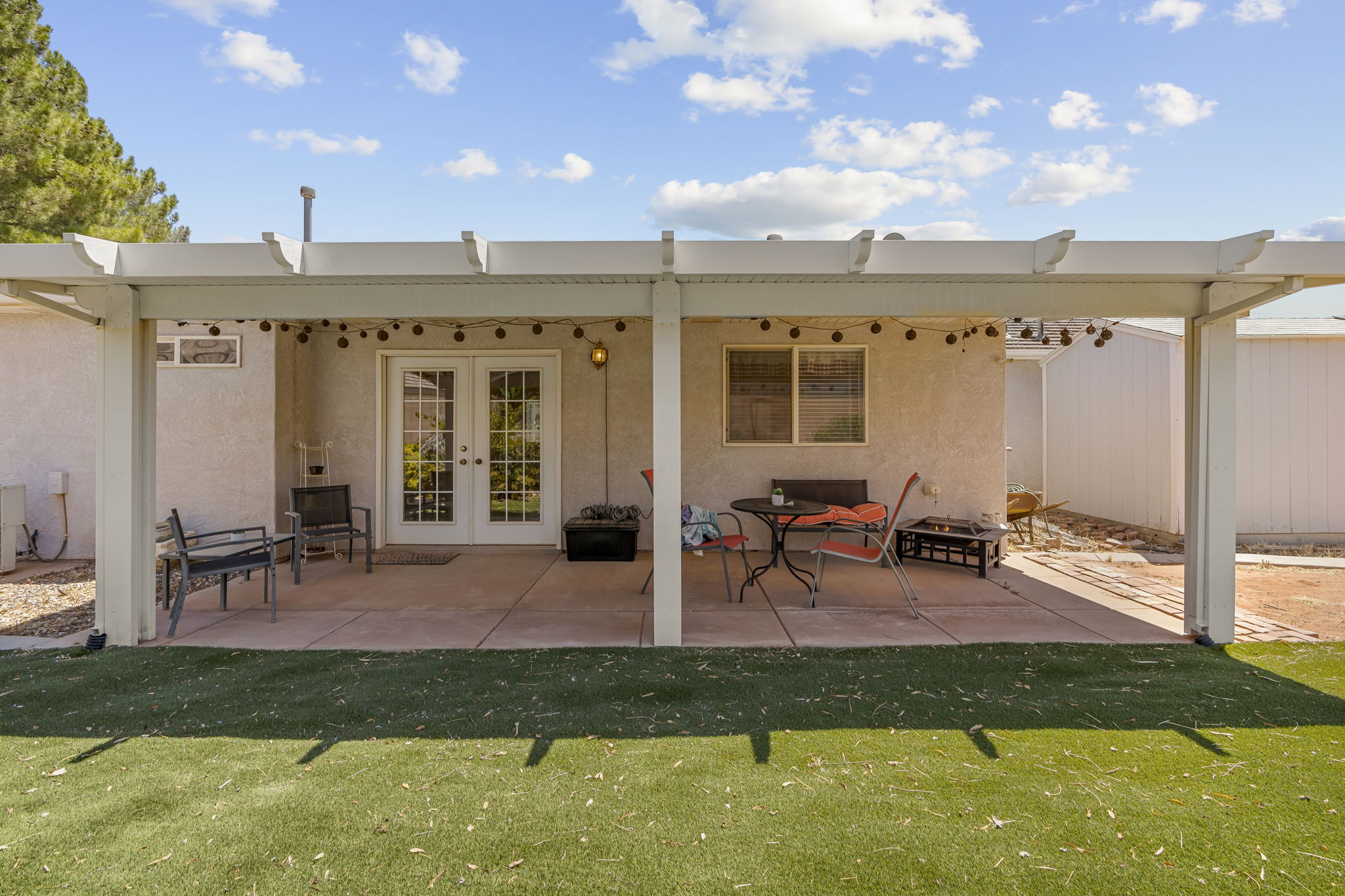 Expansive outdoor patio featuring a white pergola structure and string lighting