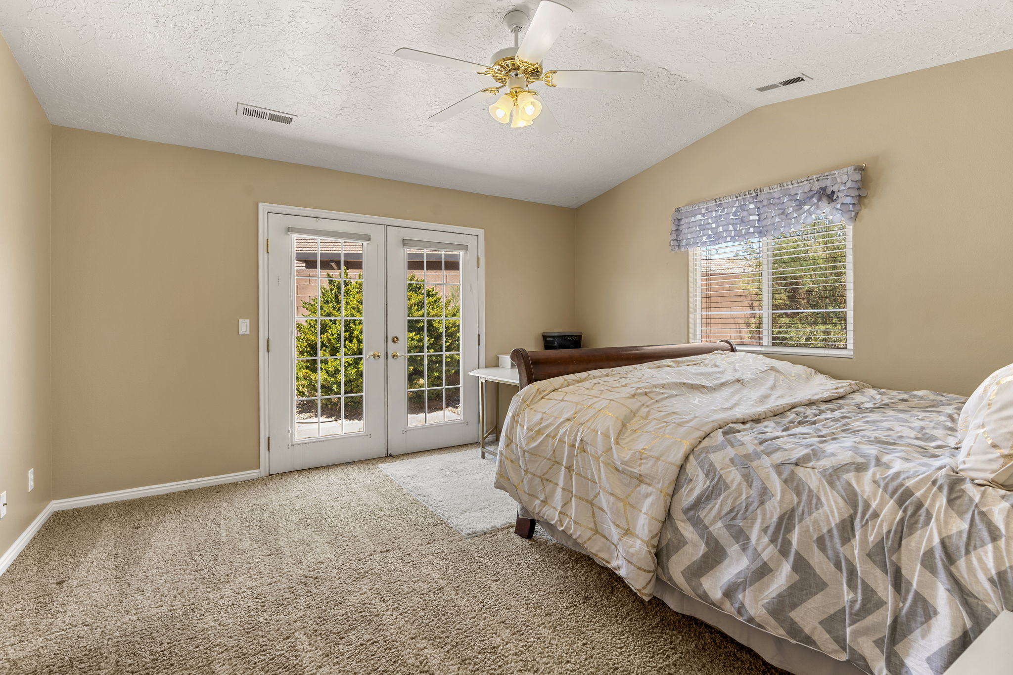 Double French doors with clear glass panes open to the exterior, complemented by a single window with blinds and a decorative valance