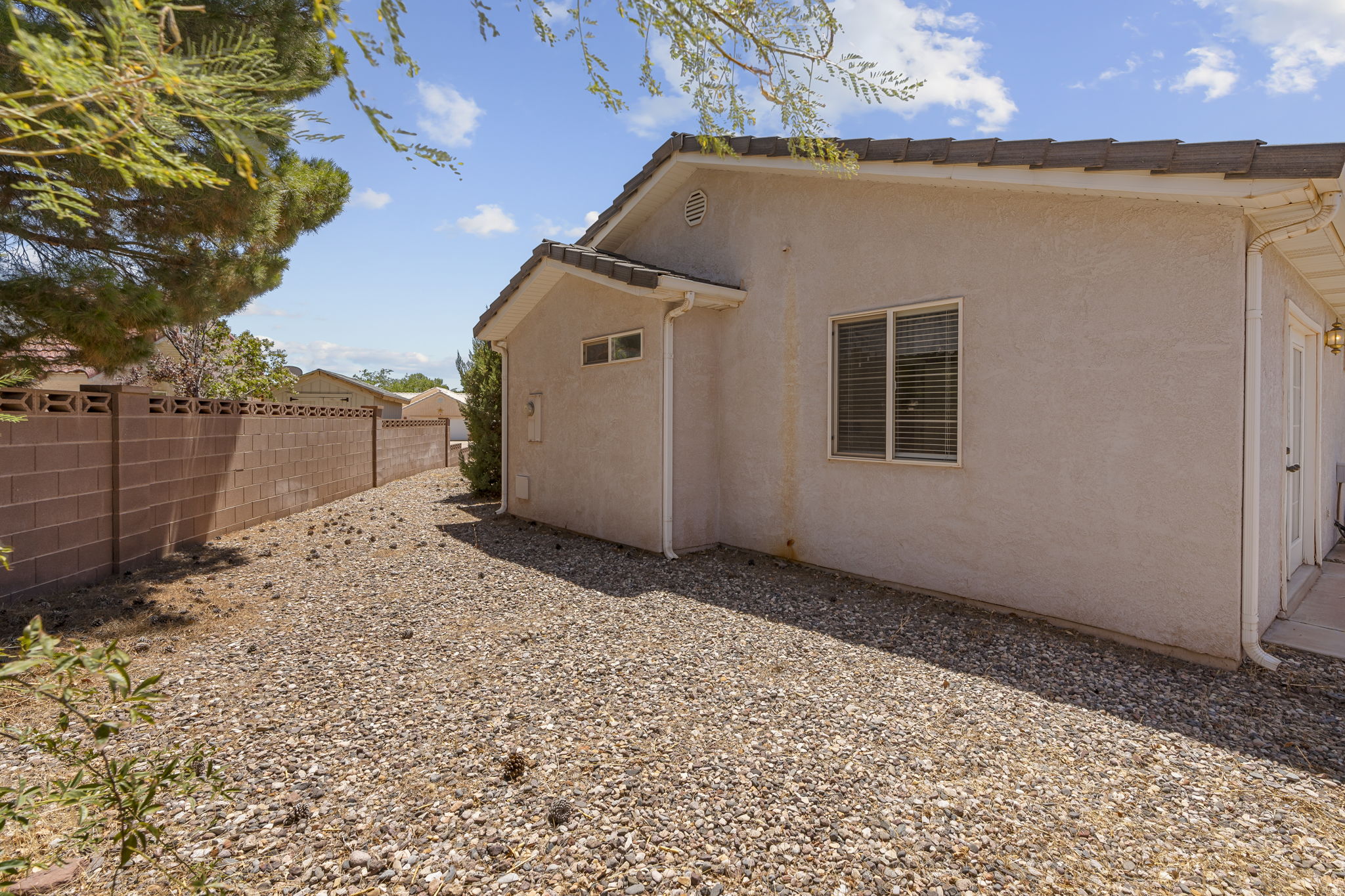 Stucco exterior featuring a dual-pane window with blinds, tile roof, and an exterior door leading to a concrete patio