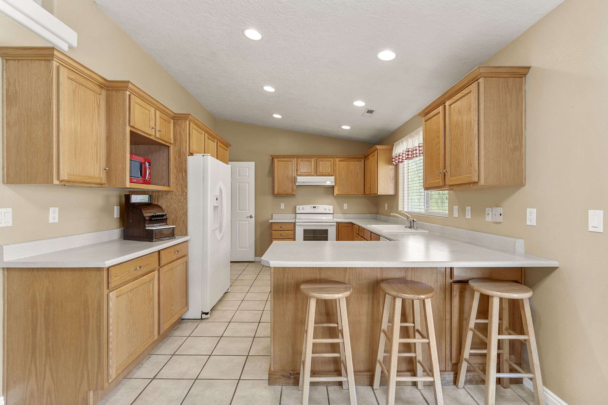 U-shaped kitchen featuring wood-finish cabinetry, white countertops, and white tile flooring