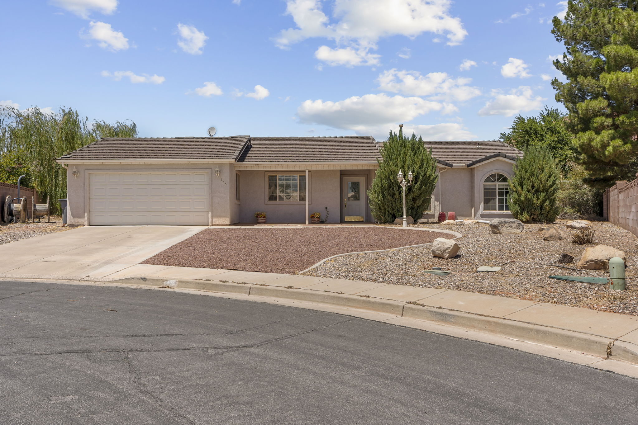 Single-story residence featuring a two-car garage, low-maintenance landscaping with rock elements, and a covered entry porch