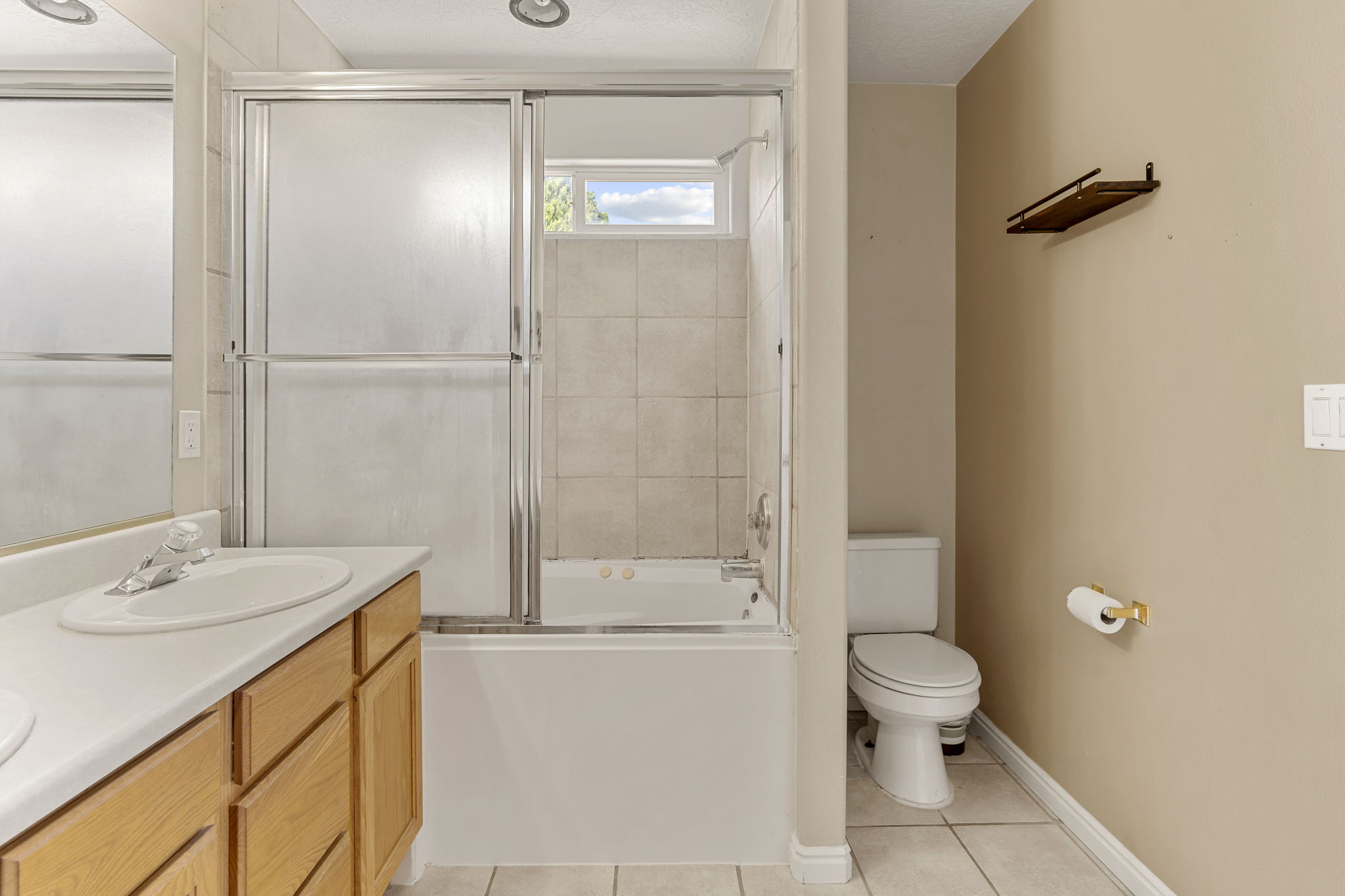 Bathroom featuring a bathtub with a tiled surround and sliding glass enclosure