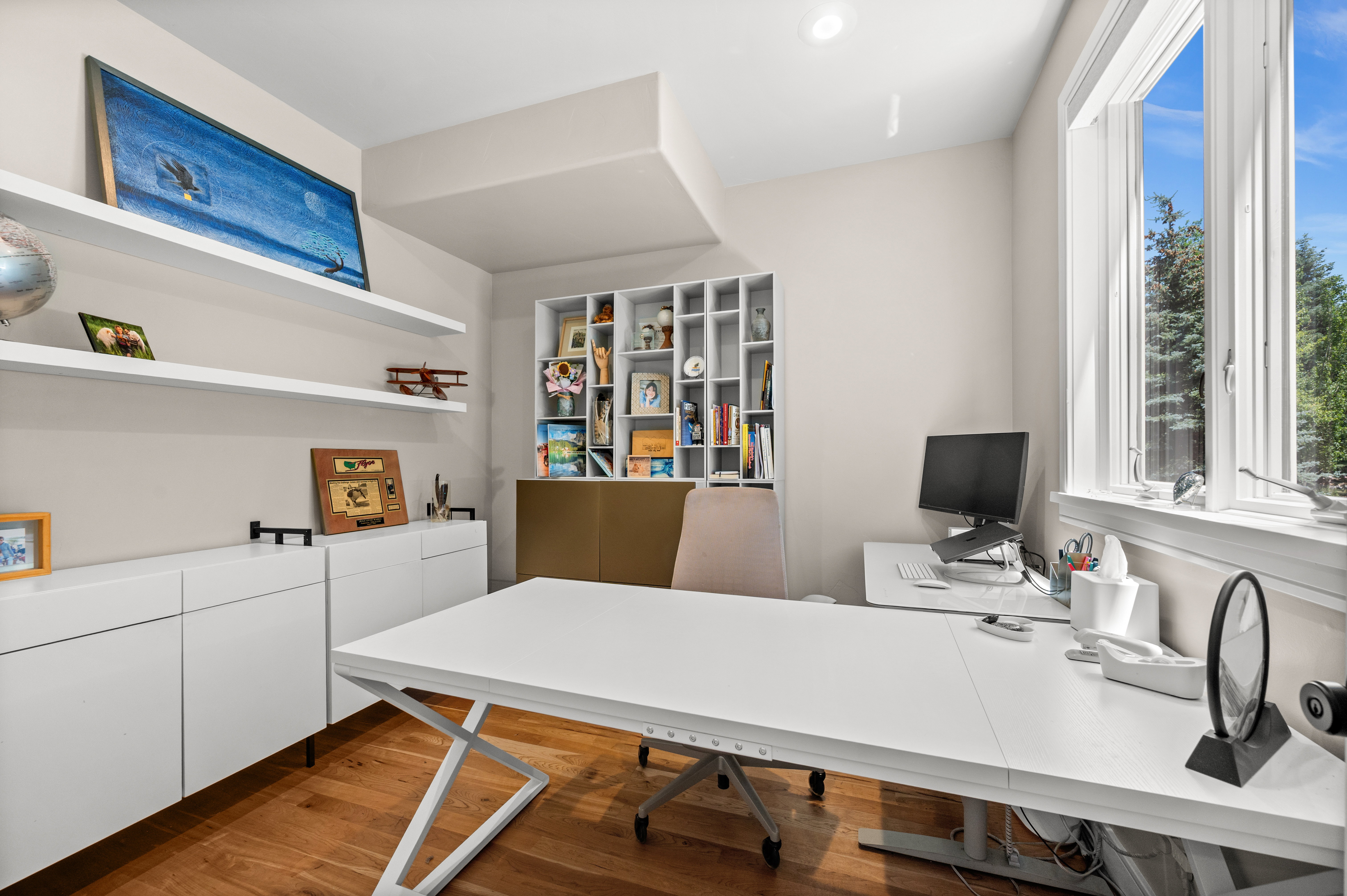 Room featuring hardwood flooring, a large window, recessed lighting, built-in shelving, and floating wall shelves