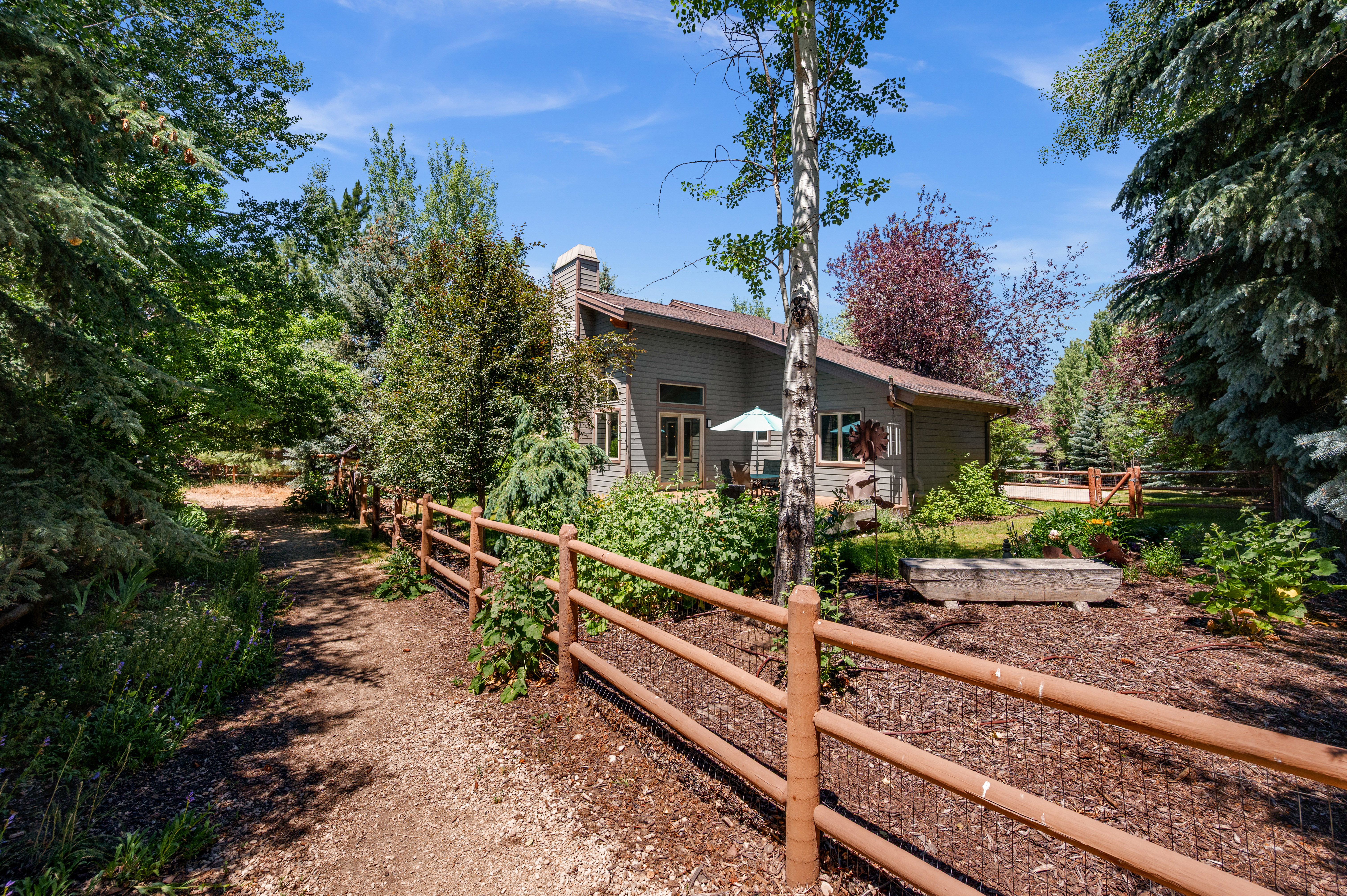 Expansive natural landscaping with a meandering path and rustic split-rail fencing