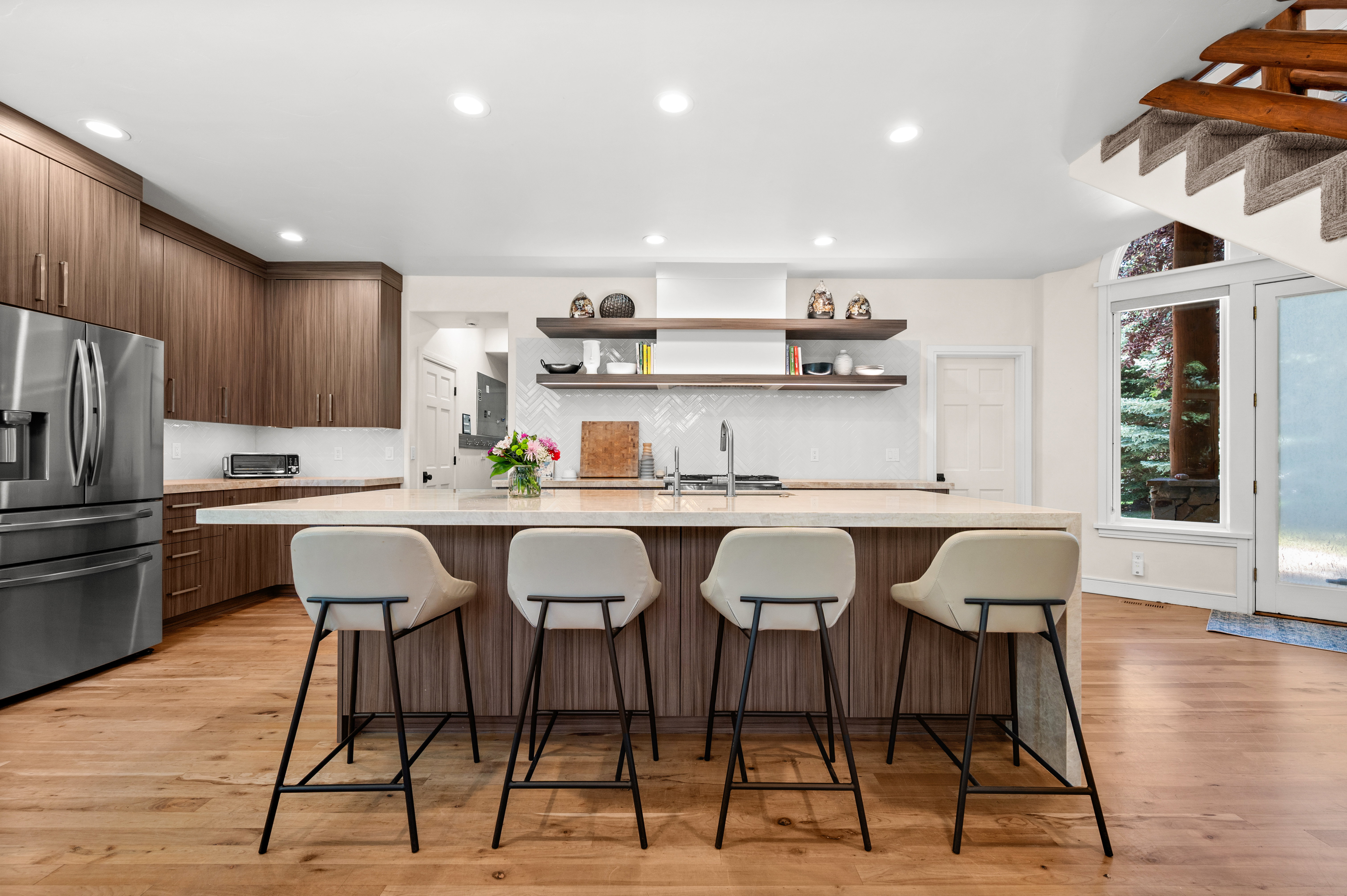 Spacious kitchen featuring an expansive center island, integrated sink, wood-finish cabinetry, and light wood flooring