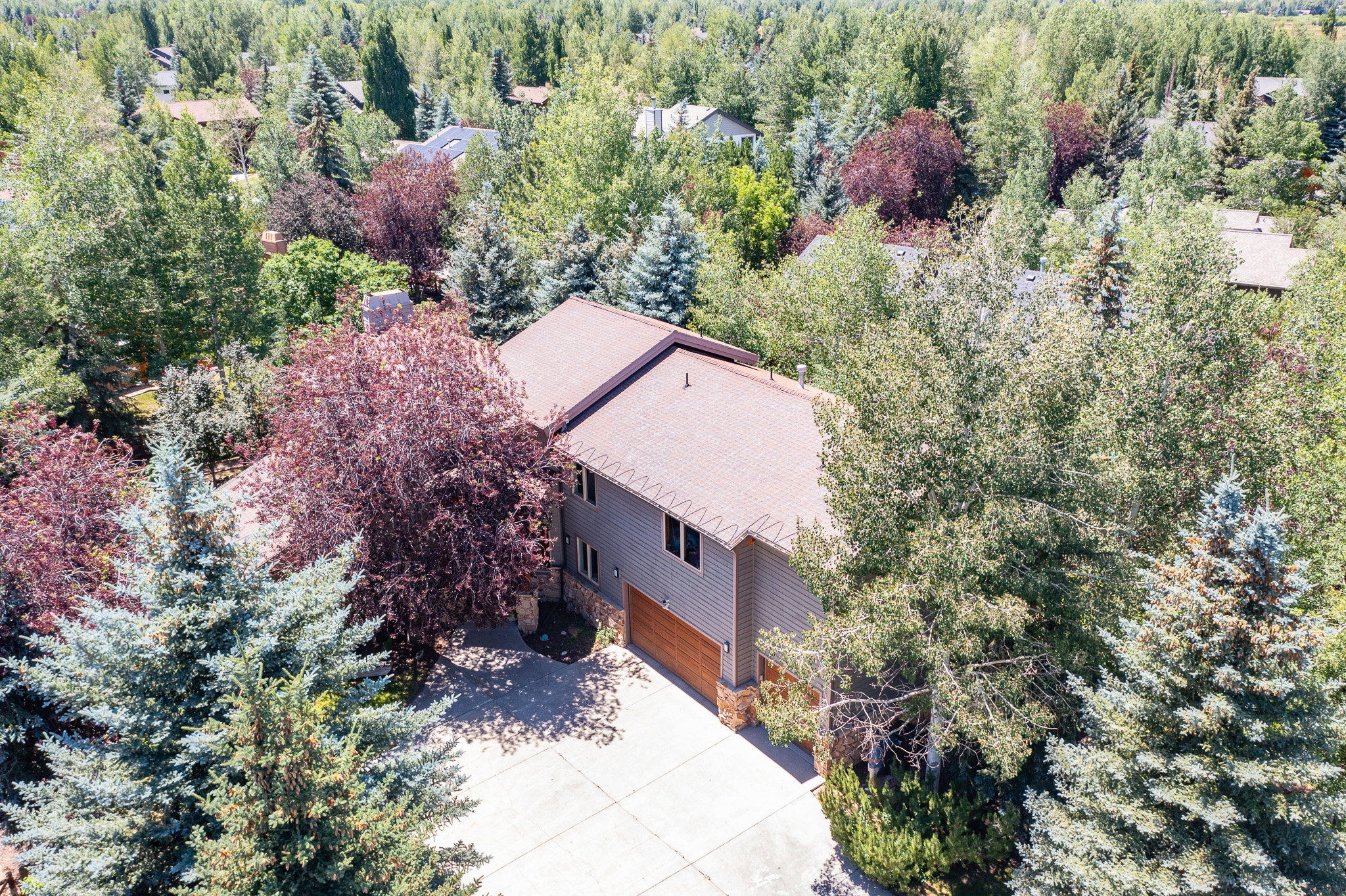 Two-story residence featuring composite siding, a stone base, an attached two-car garage with a wood-finish door, and a concrete driveway