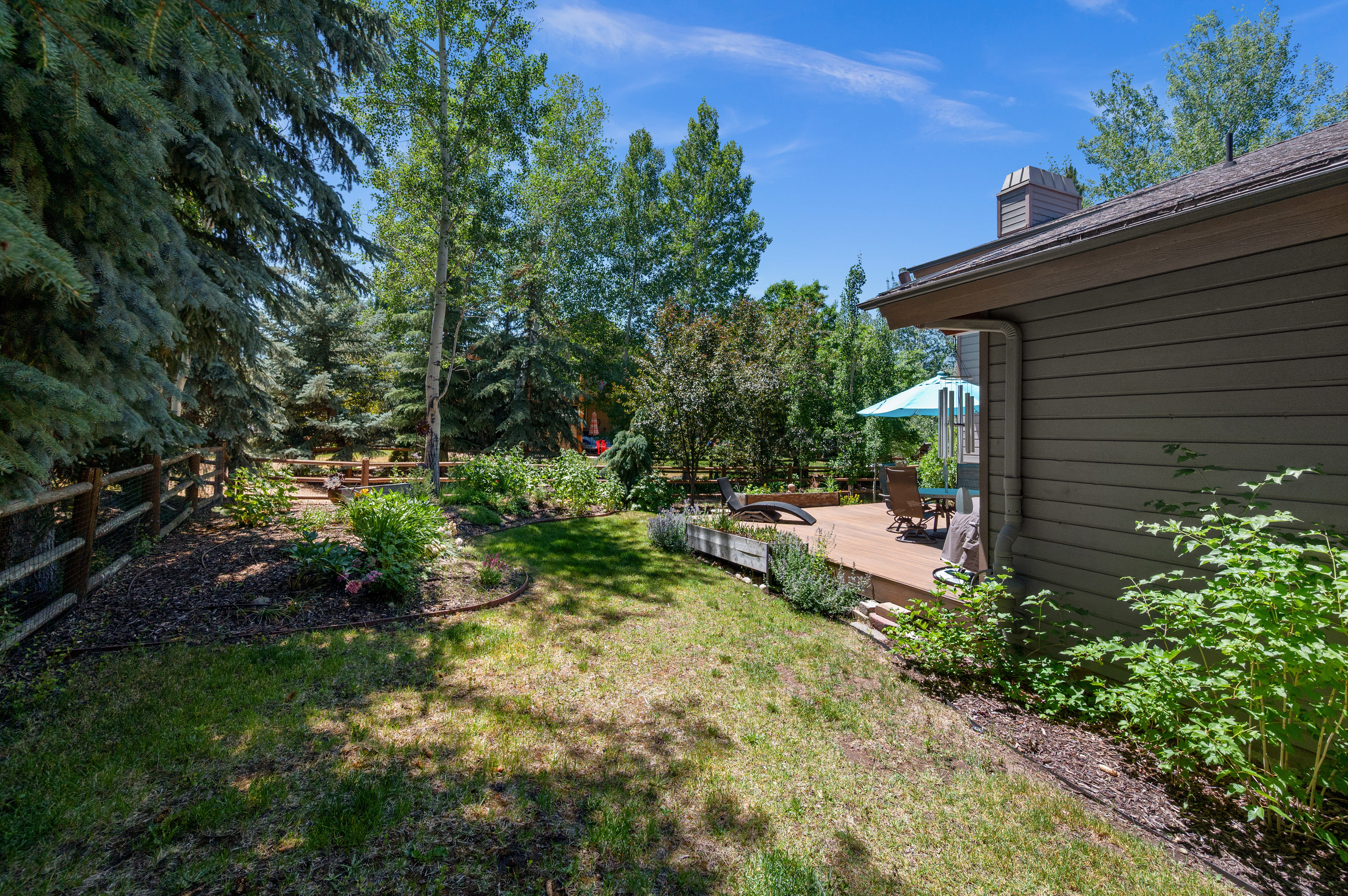 Expansive wood deck with ample room for seating, surrounded by mature trees and lush landscaping