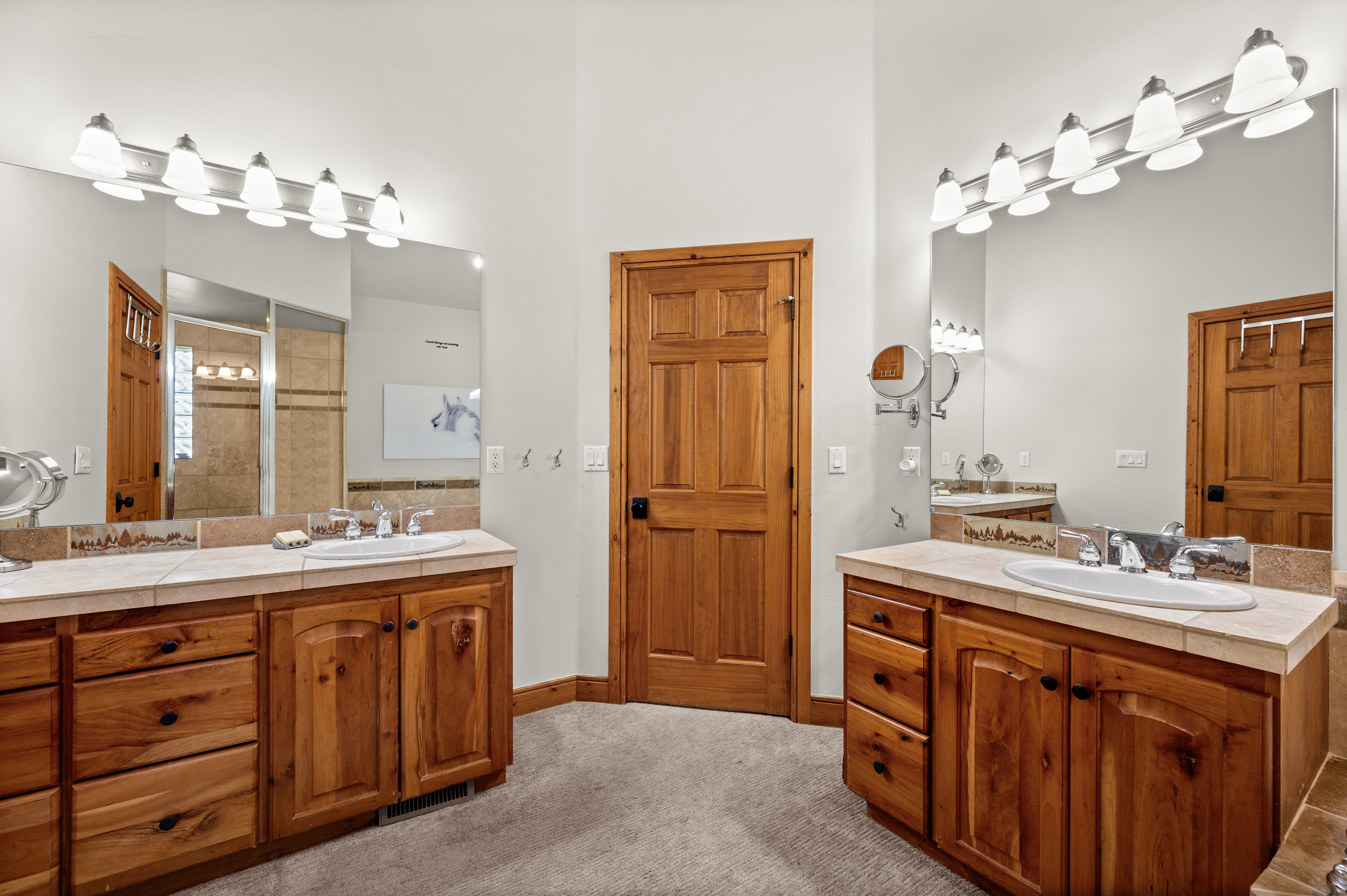 Double vanity with light wood cabinetry and beige tiled countertops