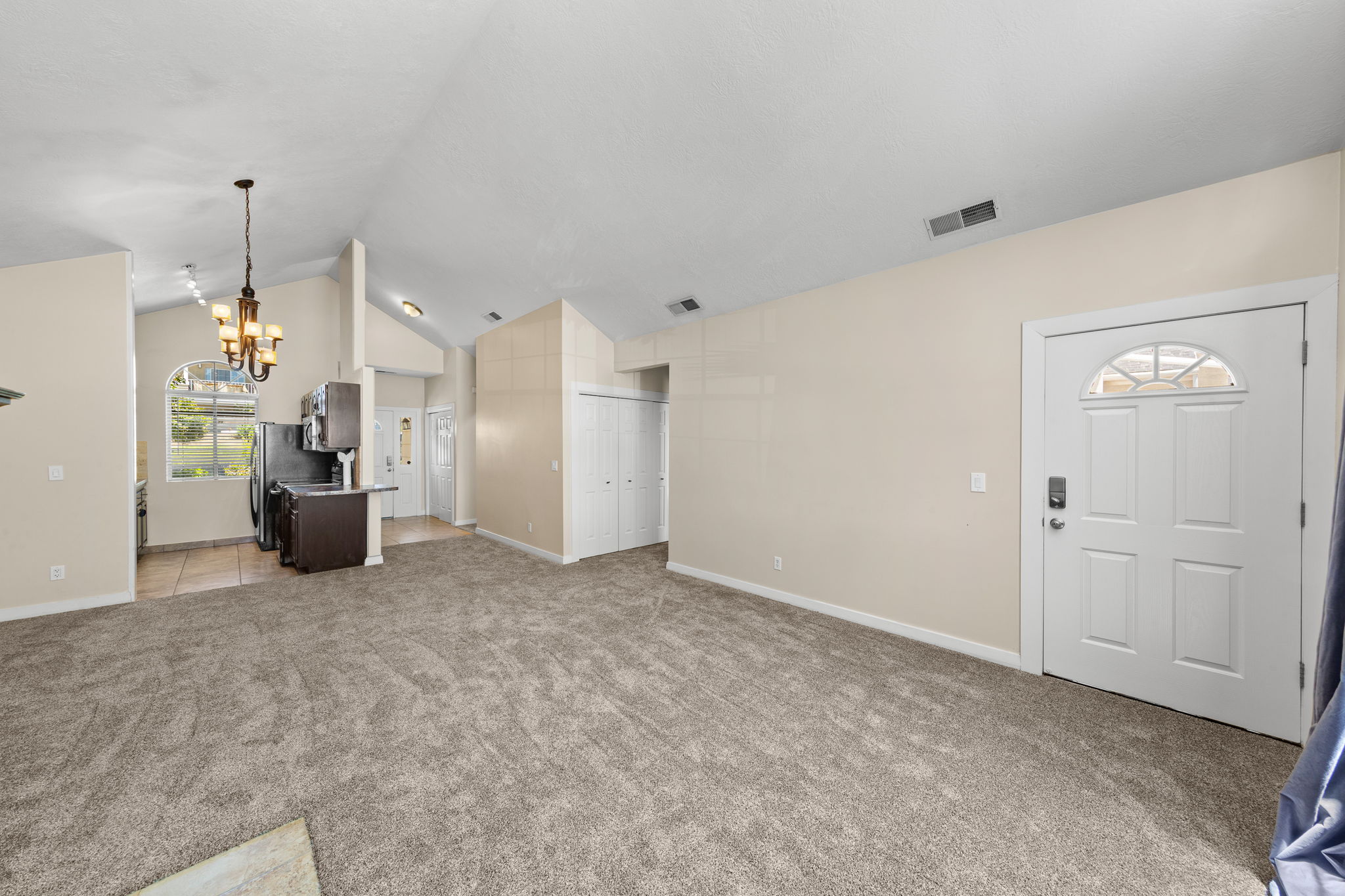Spacious living area featuring vaulted ceilings and neutral carpeting