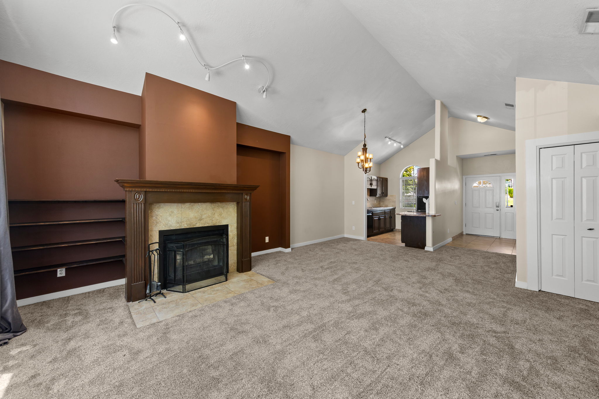 Spacious interior featuring a vaulted ceiling and an ornate fireplace with a stone surround