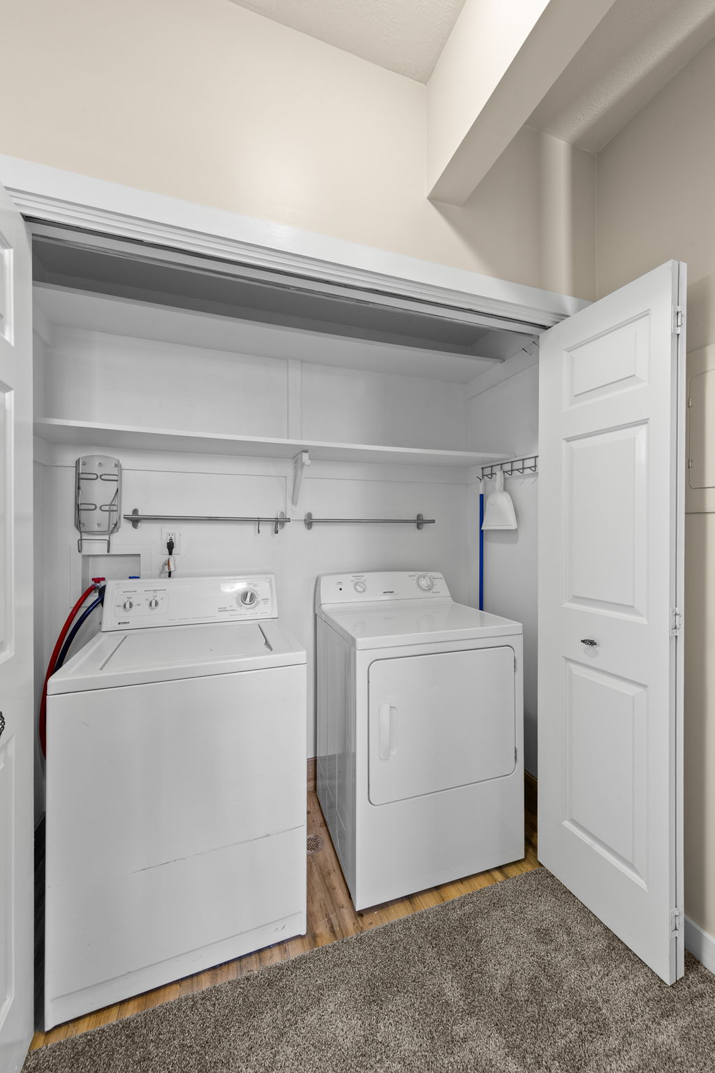 Dedicated laundry closet featuring a built-in shelf, hanging rod, and wood-finish flooring