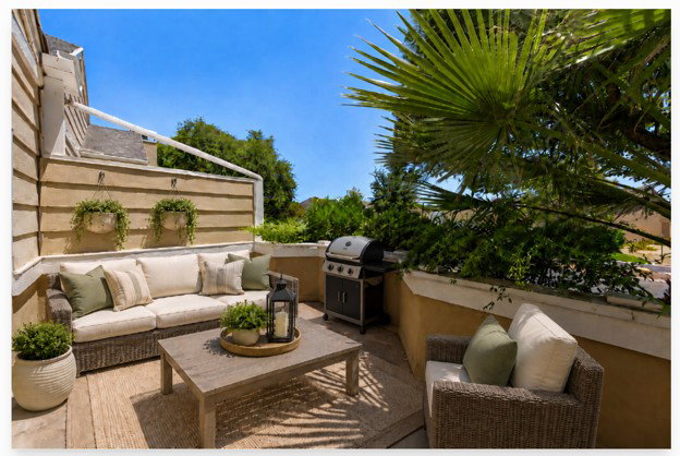Outdoor patio space featuring a built-in privacy wall, a hard surface floor, and mature landscaping