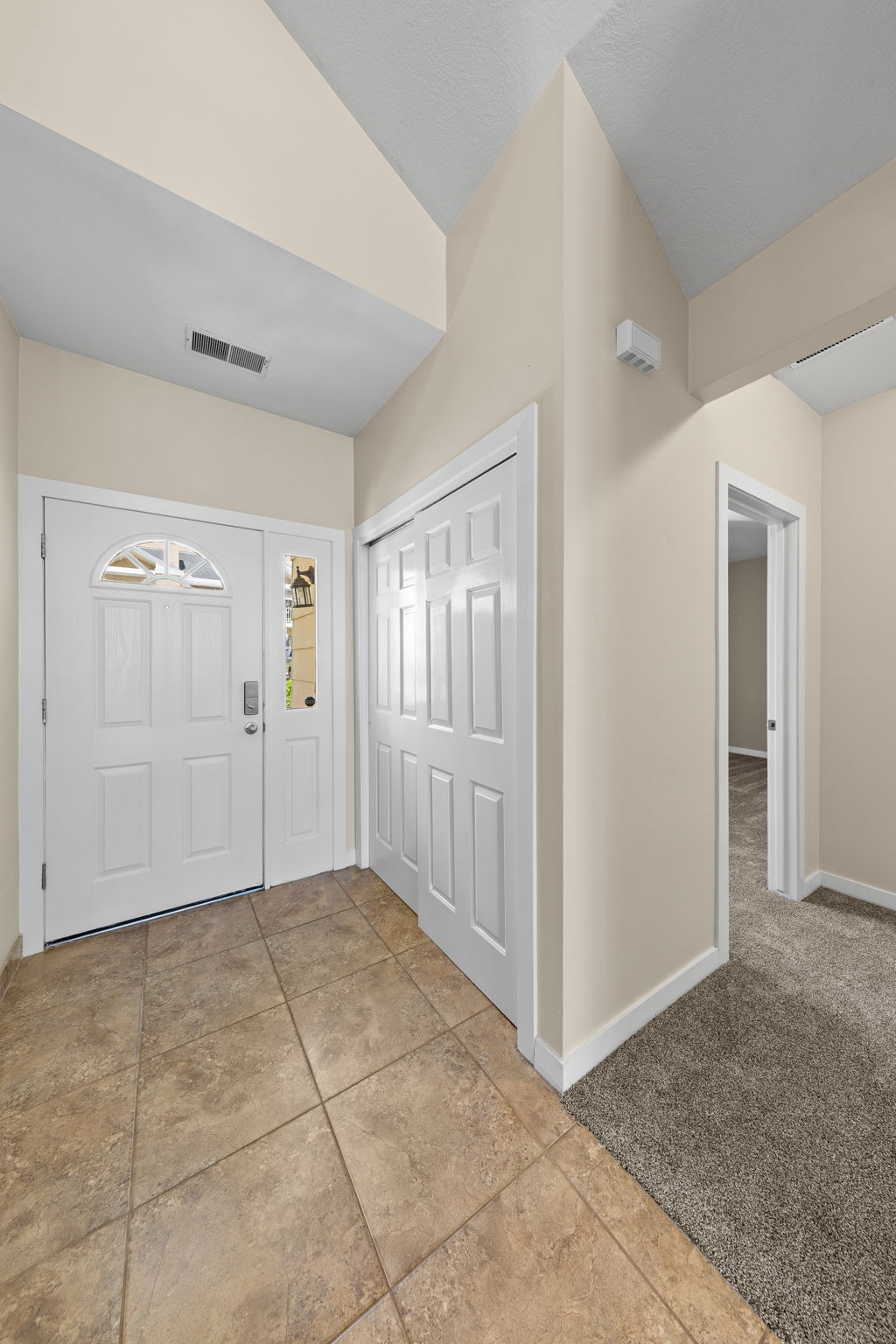 Foyer entry featuring ceramic tile flooring, a double front door with decorative glass inserts, and a bifold door closet