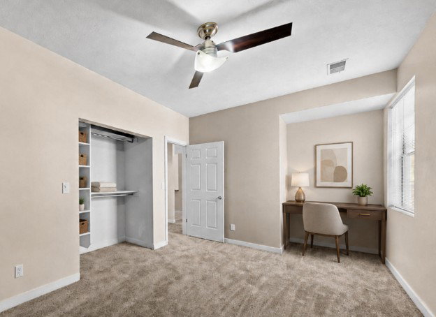 Carpeted room featuring a ceiling fan with light, a built-in closet with shelving, a window with blinds, and a paneled interior door