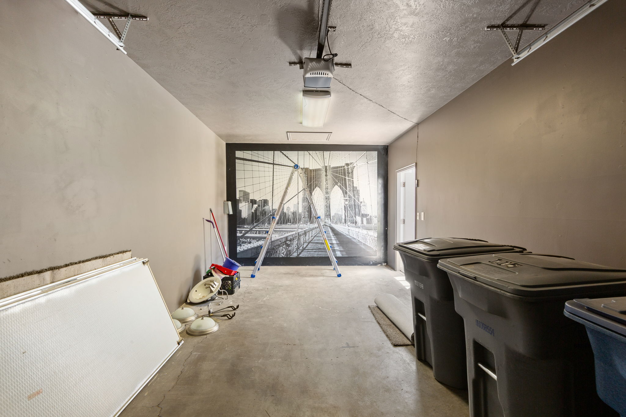 Spacious garage interior featuring concrete flooring, painted walls, and a prominent graphic wall covering