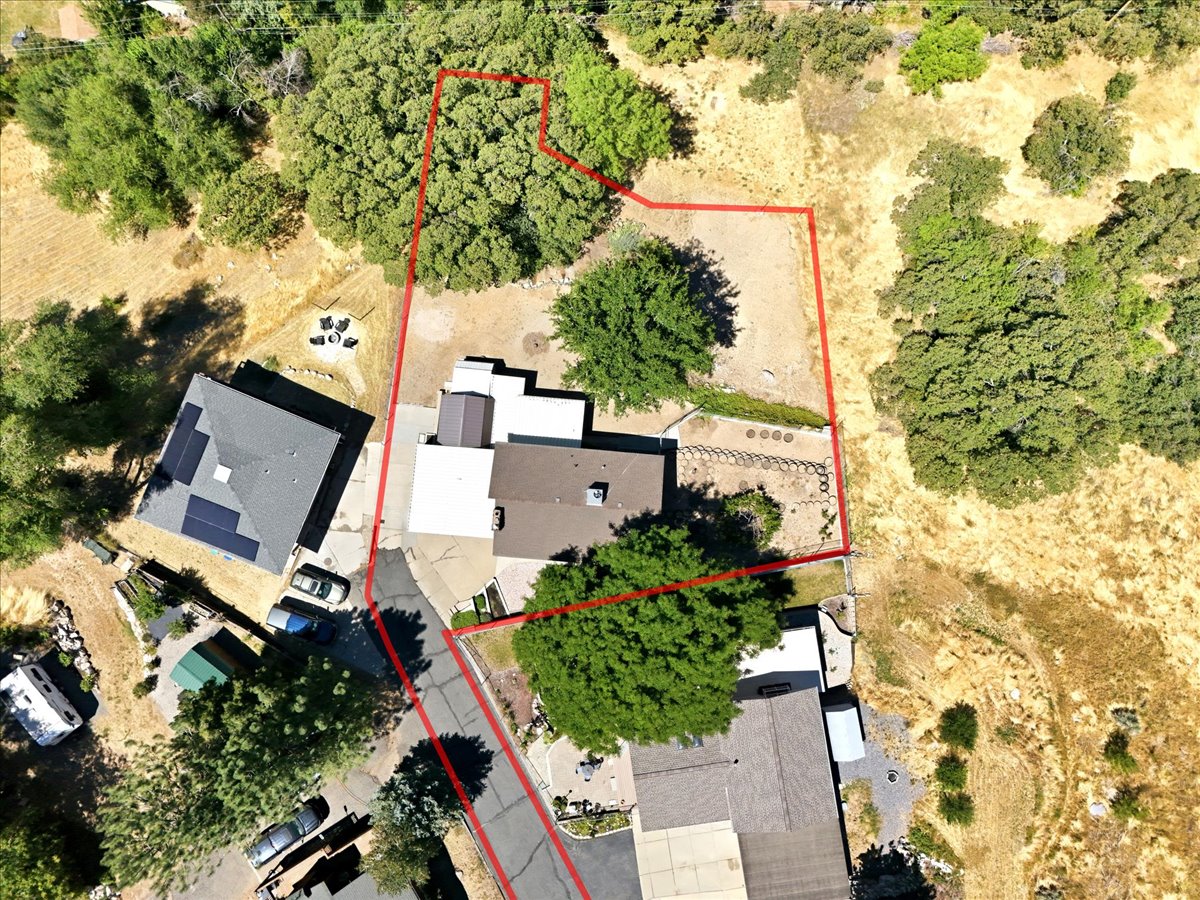 Aerial perspective showcasing an expansive property with a primary residence, detached structure, and mature trees