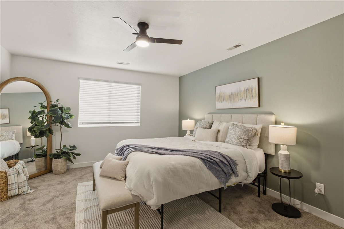 Carpeted room featuring a ceiling fan, window with blinds, and a paneled accent wall