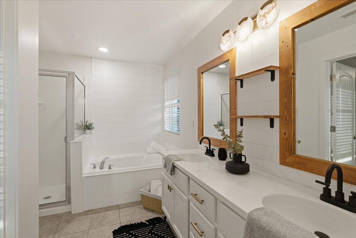 Bathroom featuring a dual vanity with white cabinetry and integrated sinks, white countertops, and matte black fixtures
