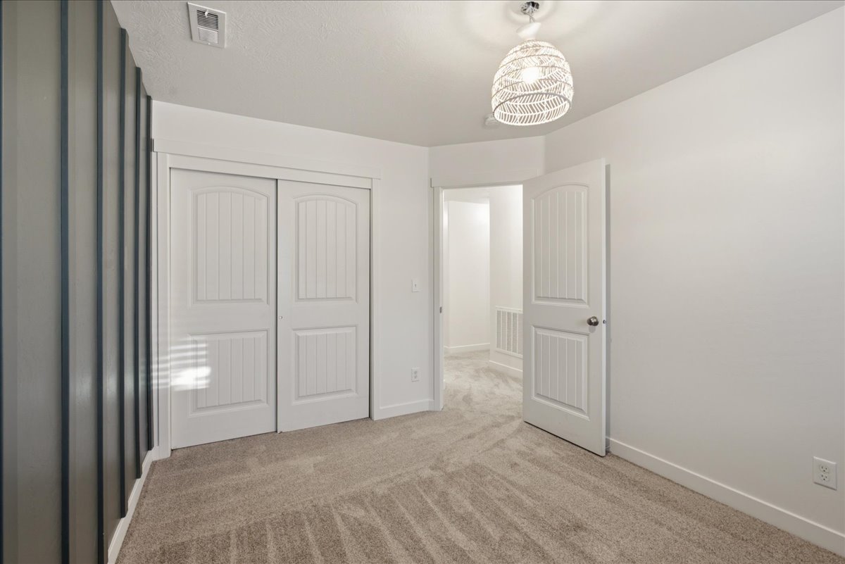 Interior room featuring neutral carpeting, white walls, and a decorative ceiling light fixture