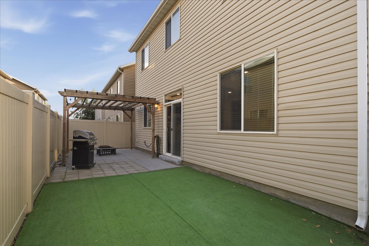 Private backyard featuring a paved patio, wooden pergola, and artificial turf