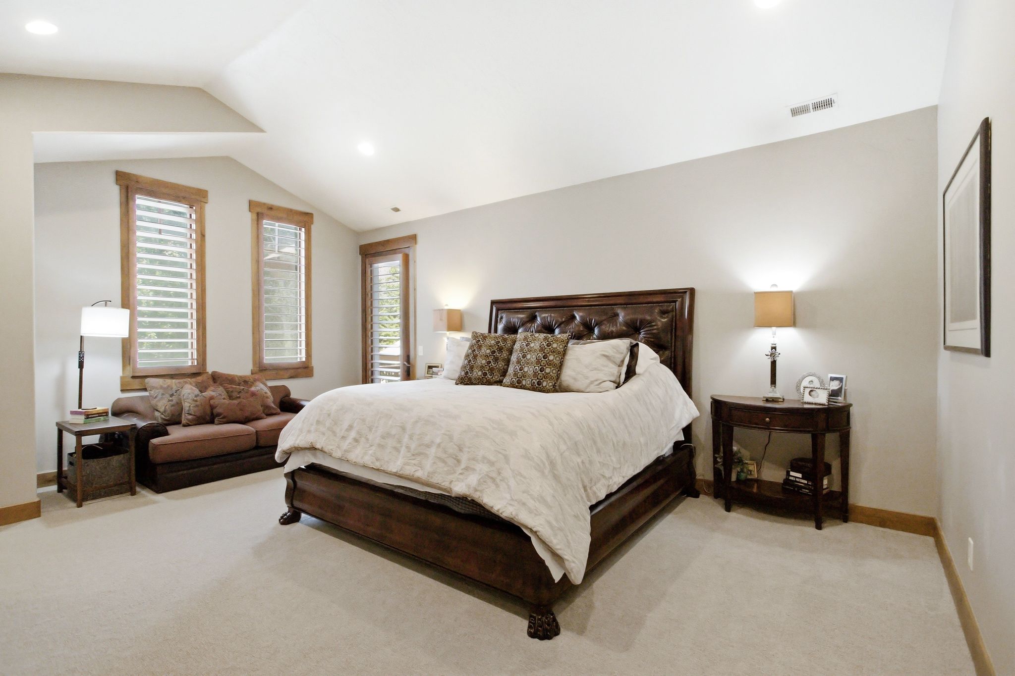 Vaulted ceiling room featuring light-toned walls and plush carpeting