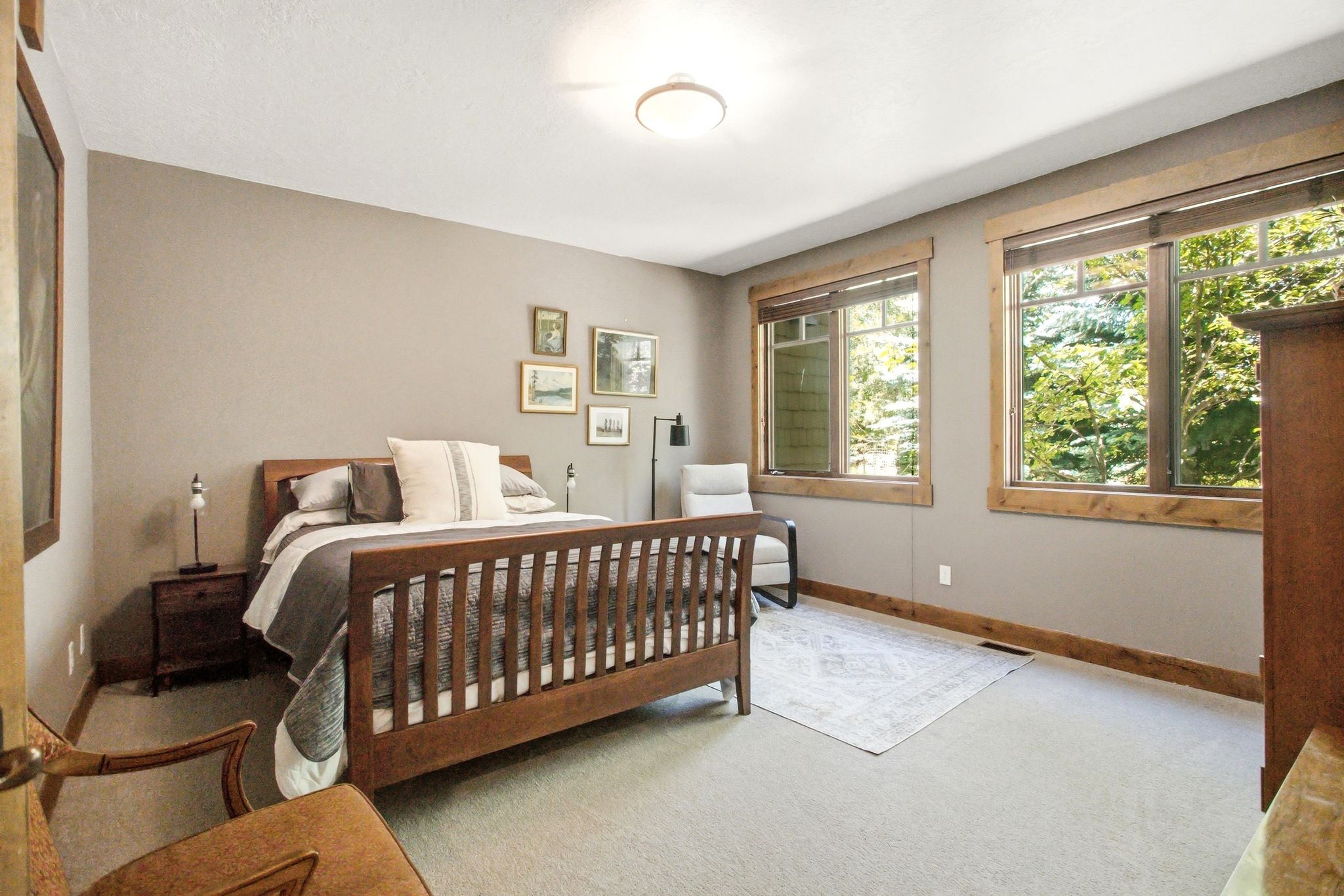 Spacious room featuring neutral painted walls, two large windows with natural wood trim, plush carpeting, and a ceiling-mounted light fixture