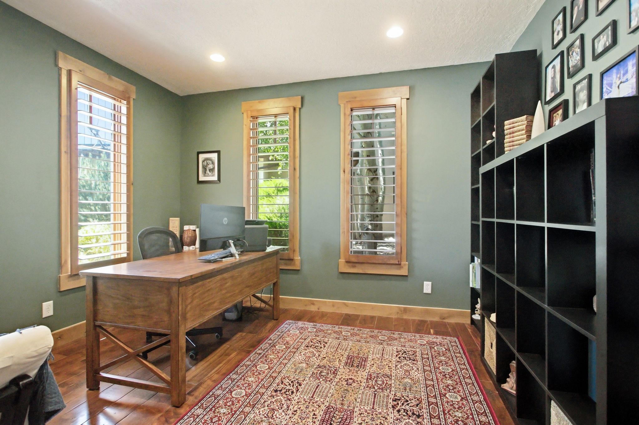 Rich wood-finish flooring complements the two windows featuring wood trim and louvered shutters