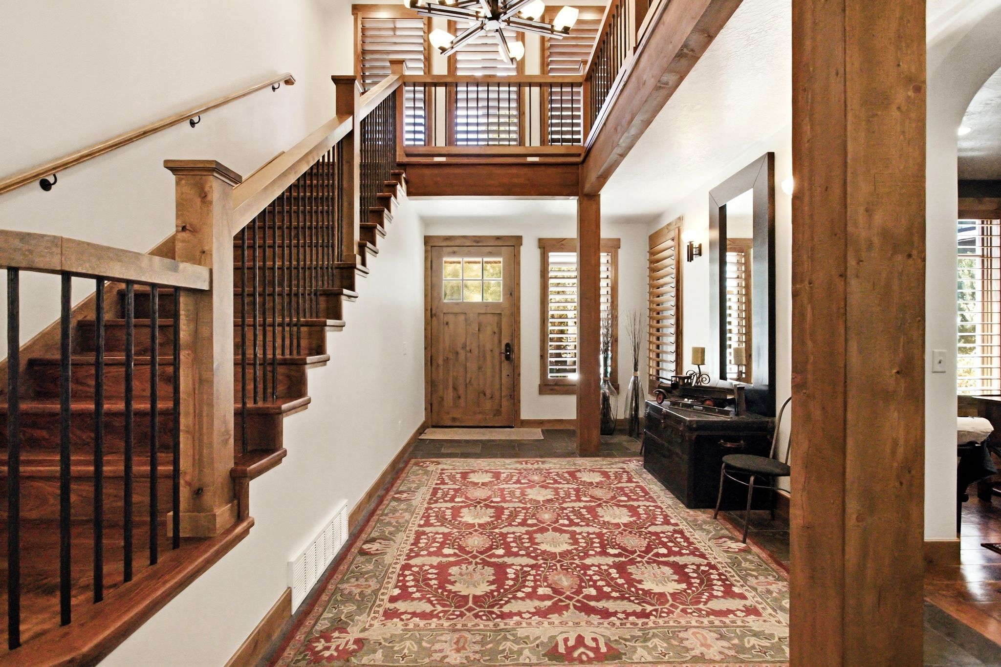 Entryway featuring a wood-panel door with glass inserts, flanked by shuttered windows