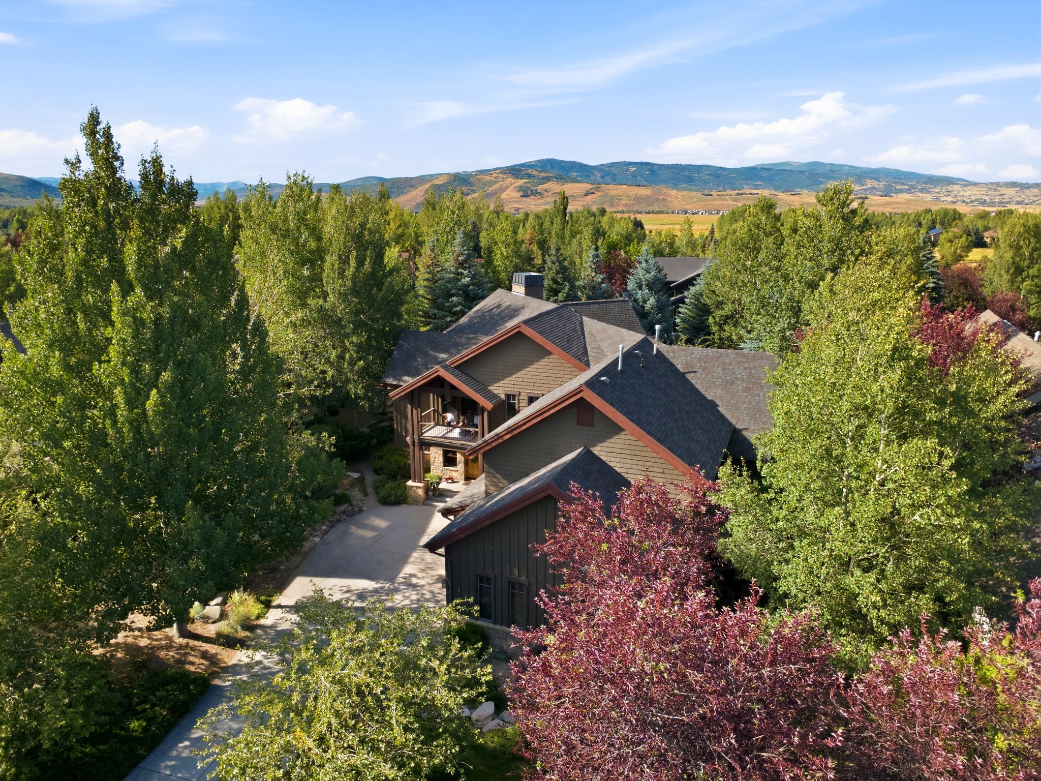 Multi-level residence featuring a dark shingle roof and natural wood siding