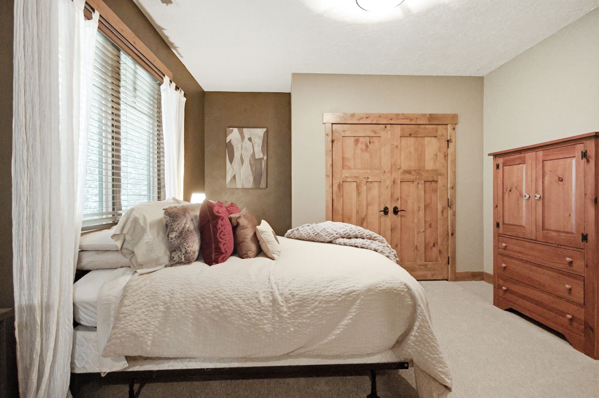 Carpeted room featuring a large window with blinds and white drapes