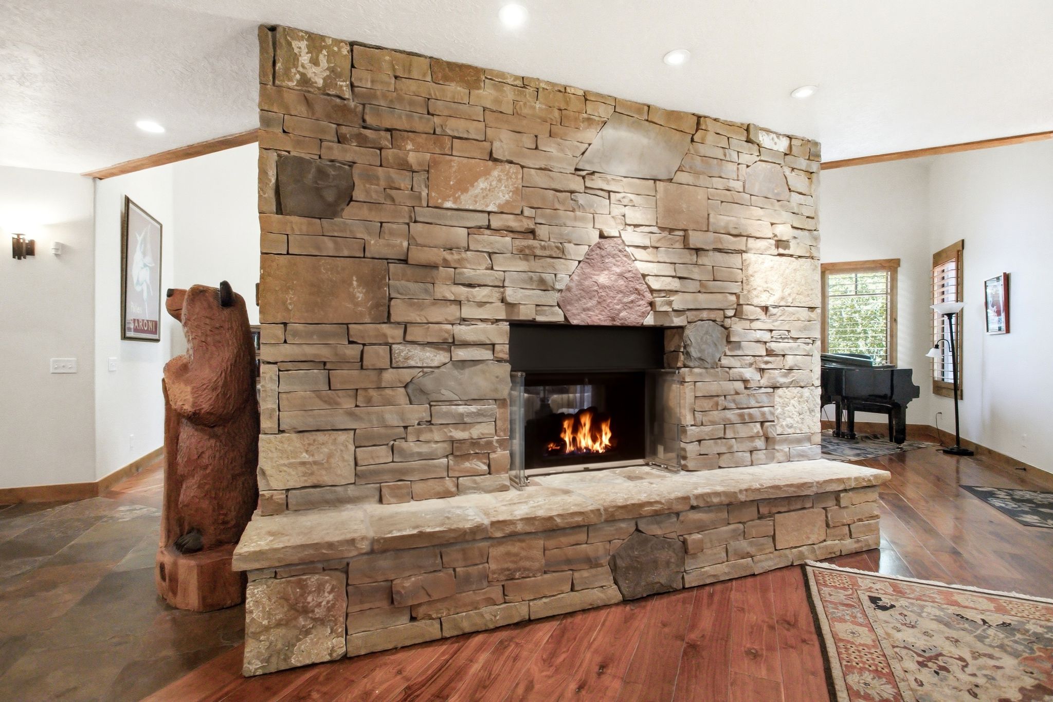 Stone fireplace with a hearth, recessed lighting, and wood-finish flooring