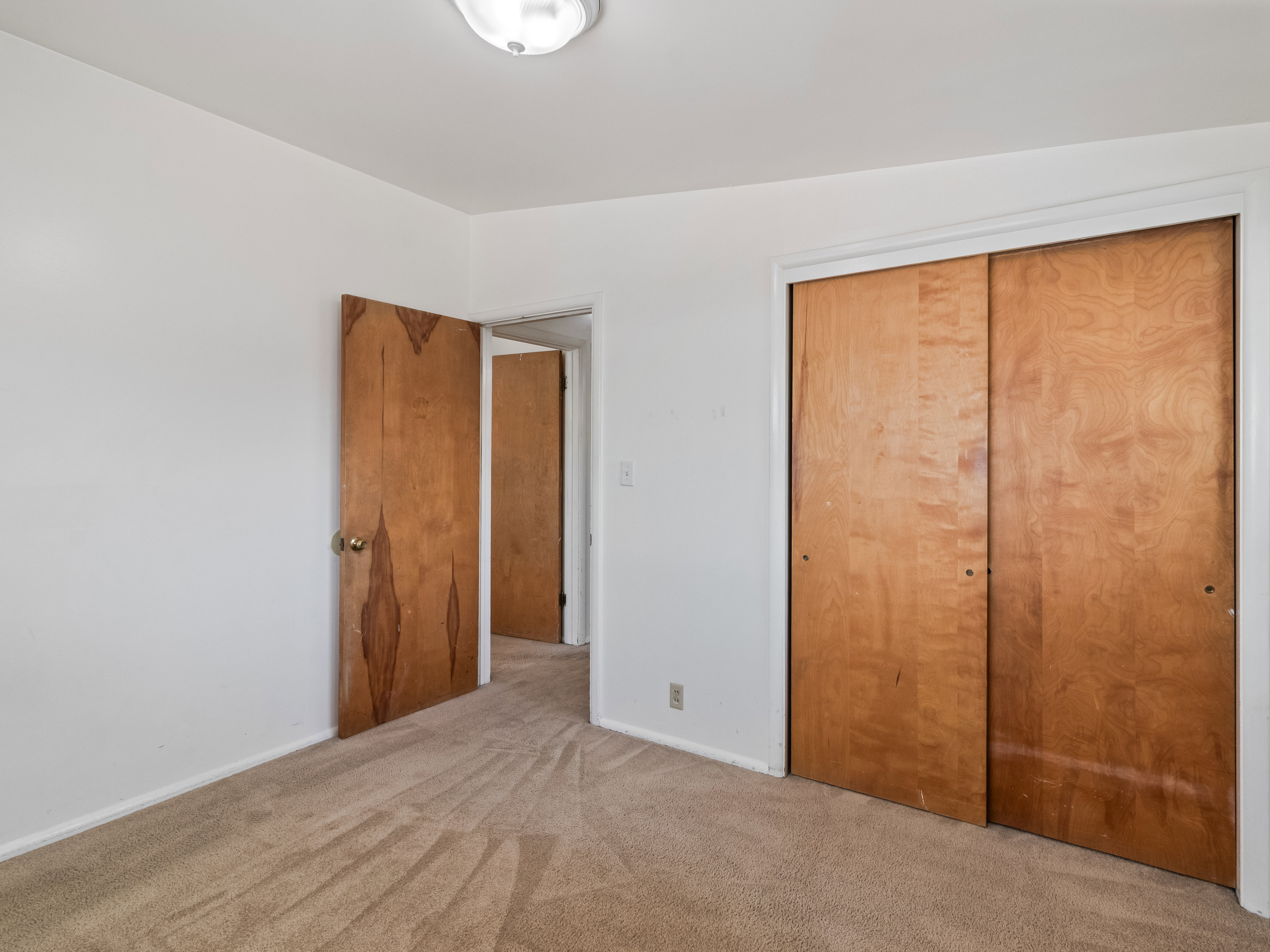 Carpeted room with a flush-mount ceiling light, white baseboards, and white walls