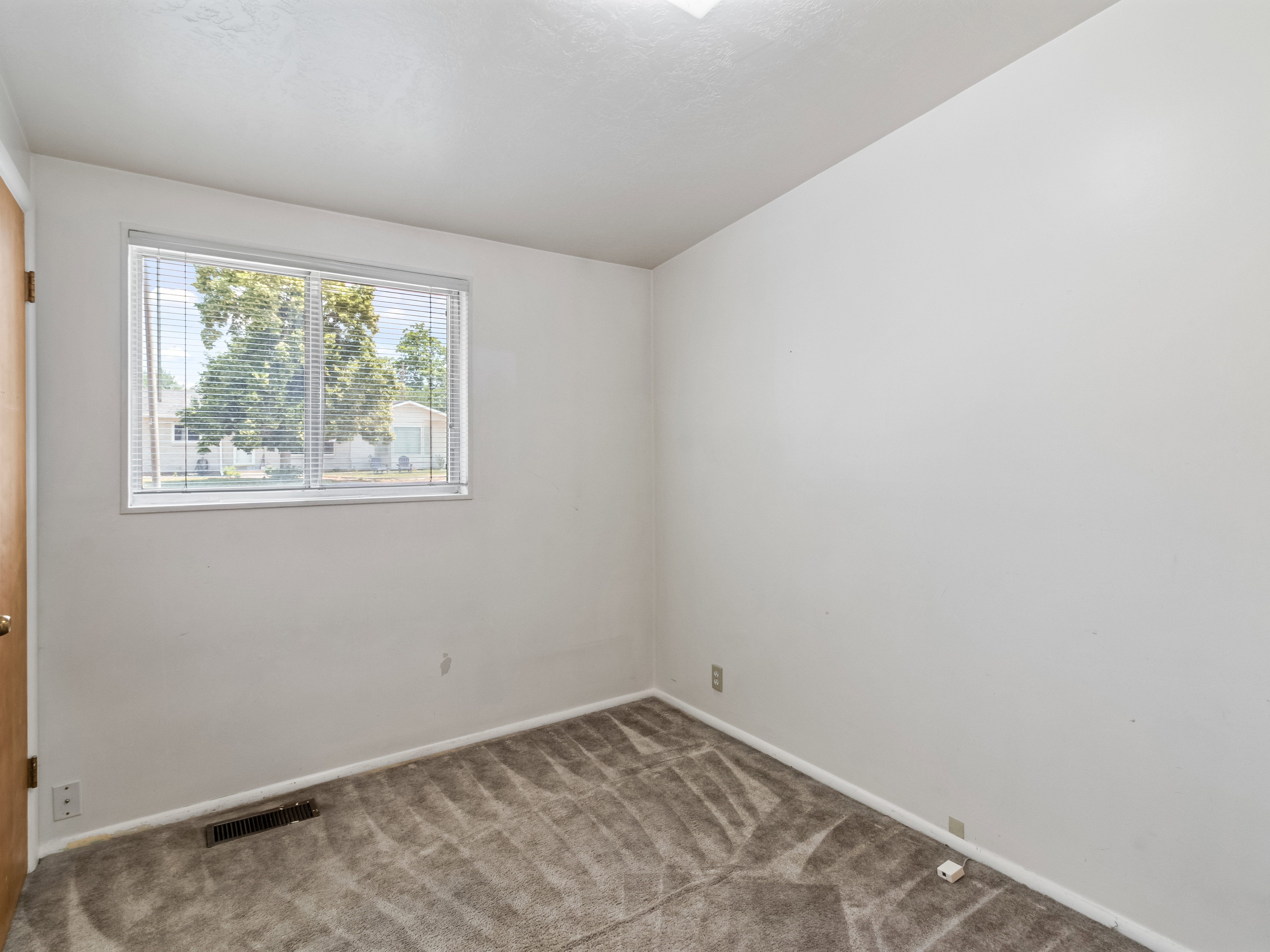Interior space featuring a window with blinds, light gray carpeting, and white painted walls