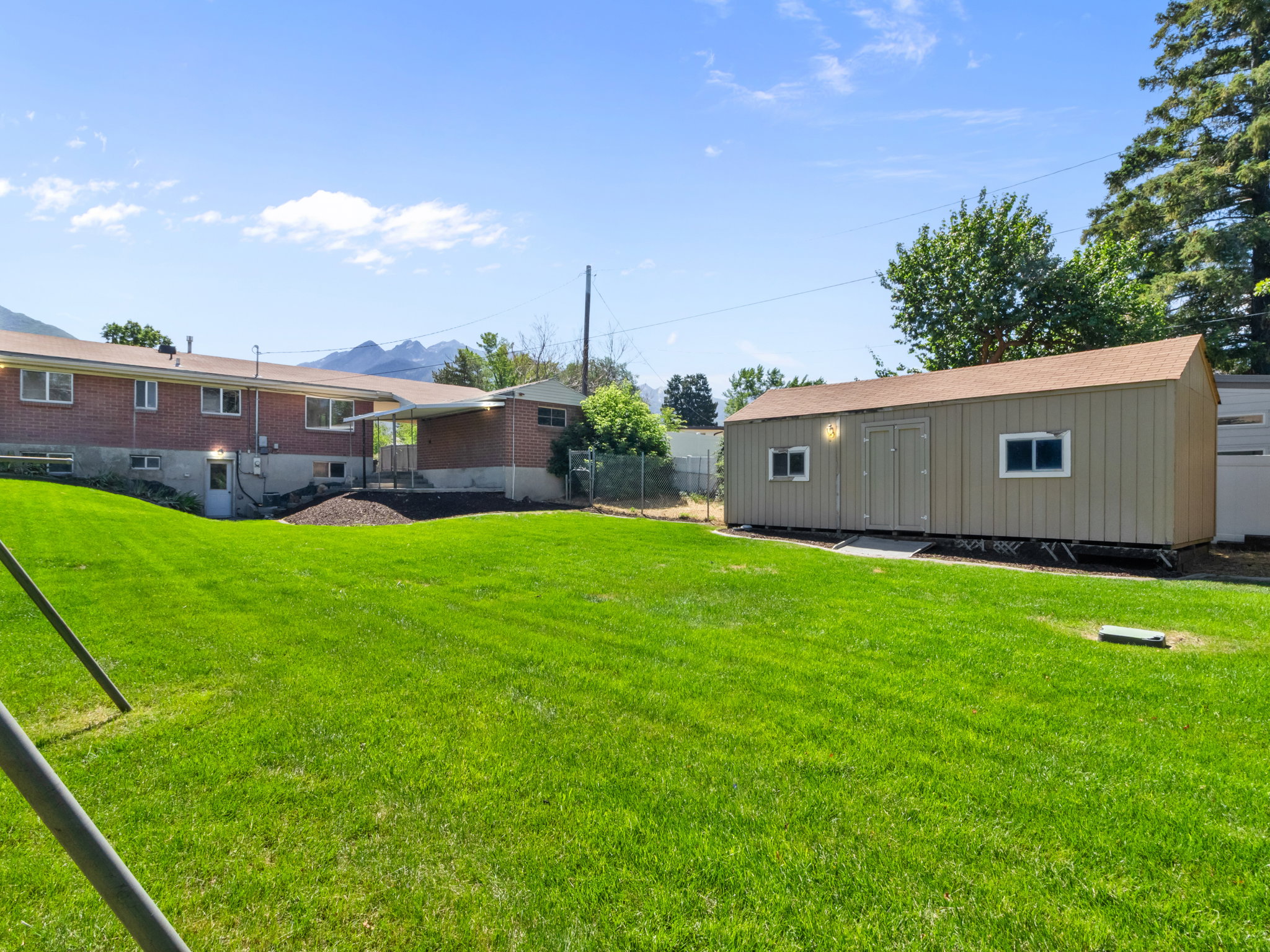 Expansive green lawn with a detached auxiliary building featuring double doors and multiple windows