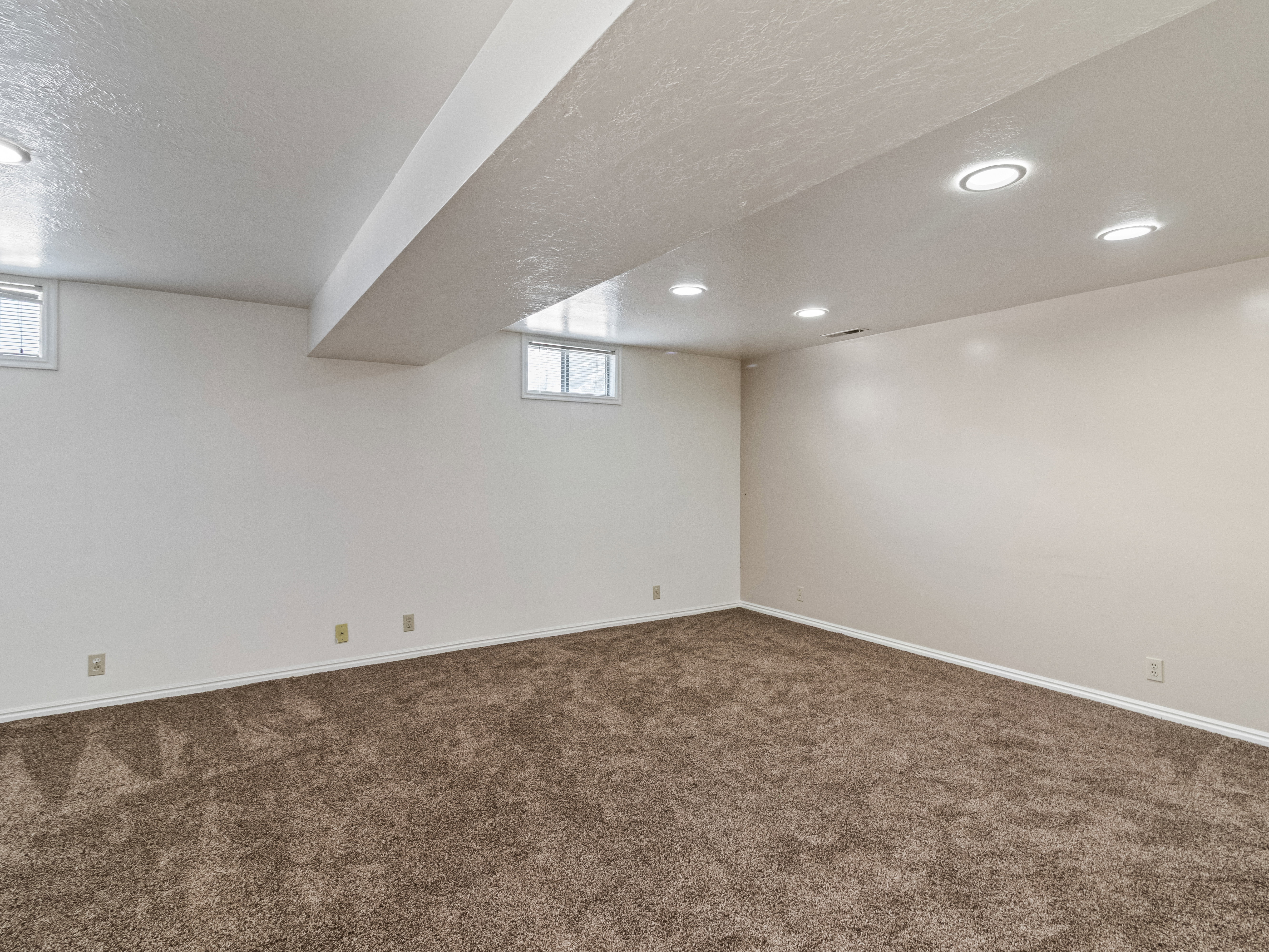Expansive room featuring recessed lighting, light-toned walls, and plush brown carpeting