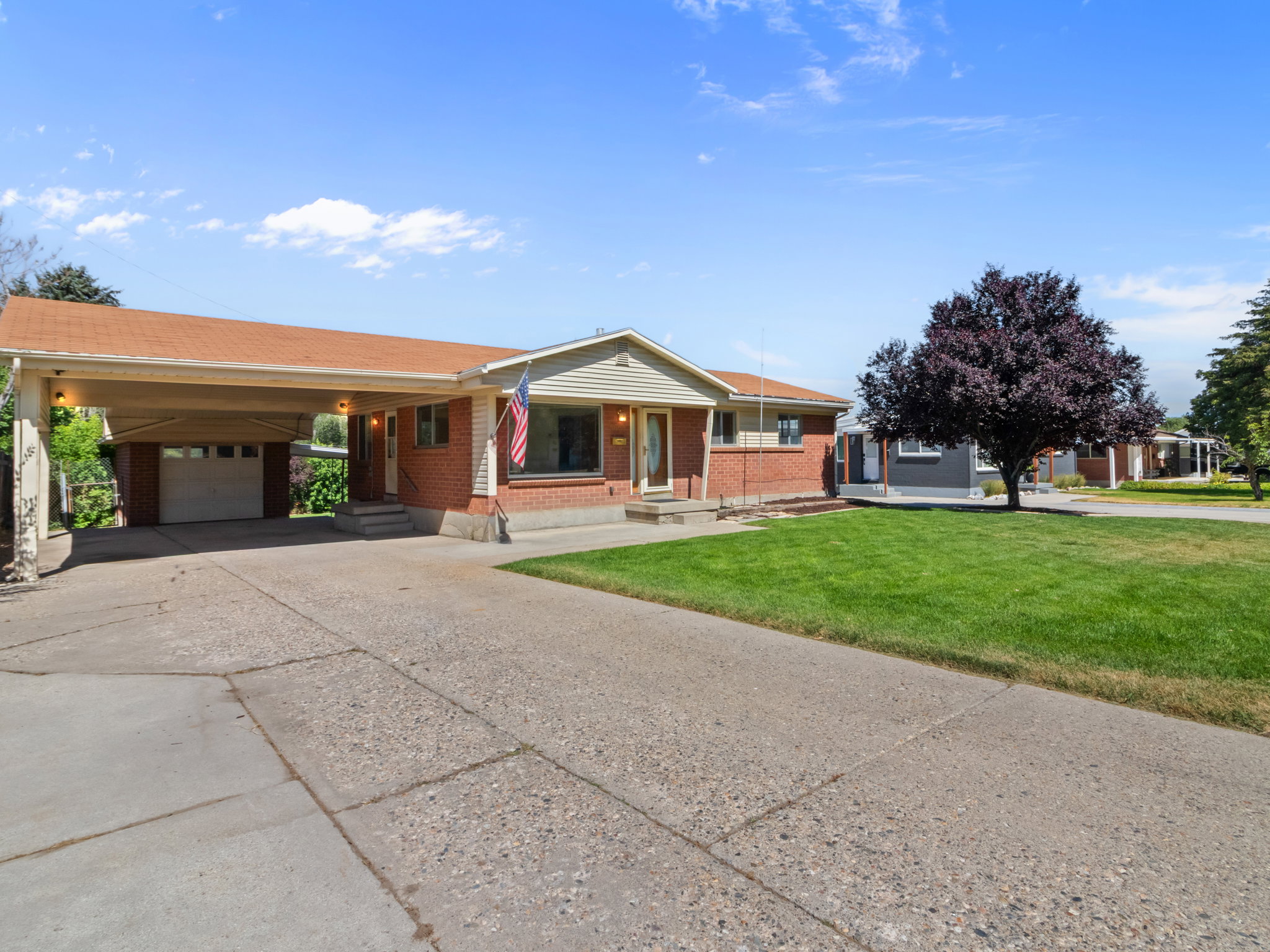 Brick and siding exterior featuring a covered carport, attached garage, and a concrete driveway