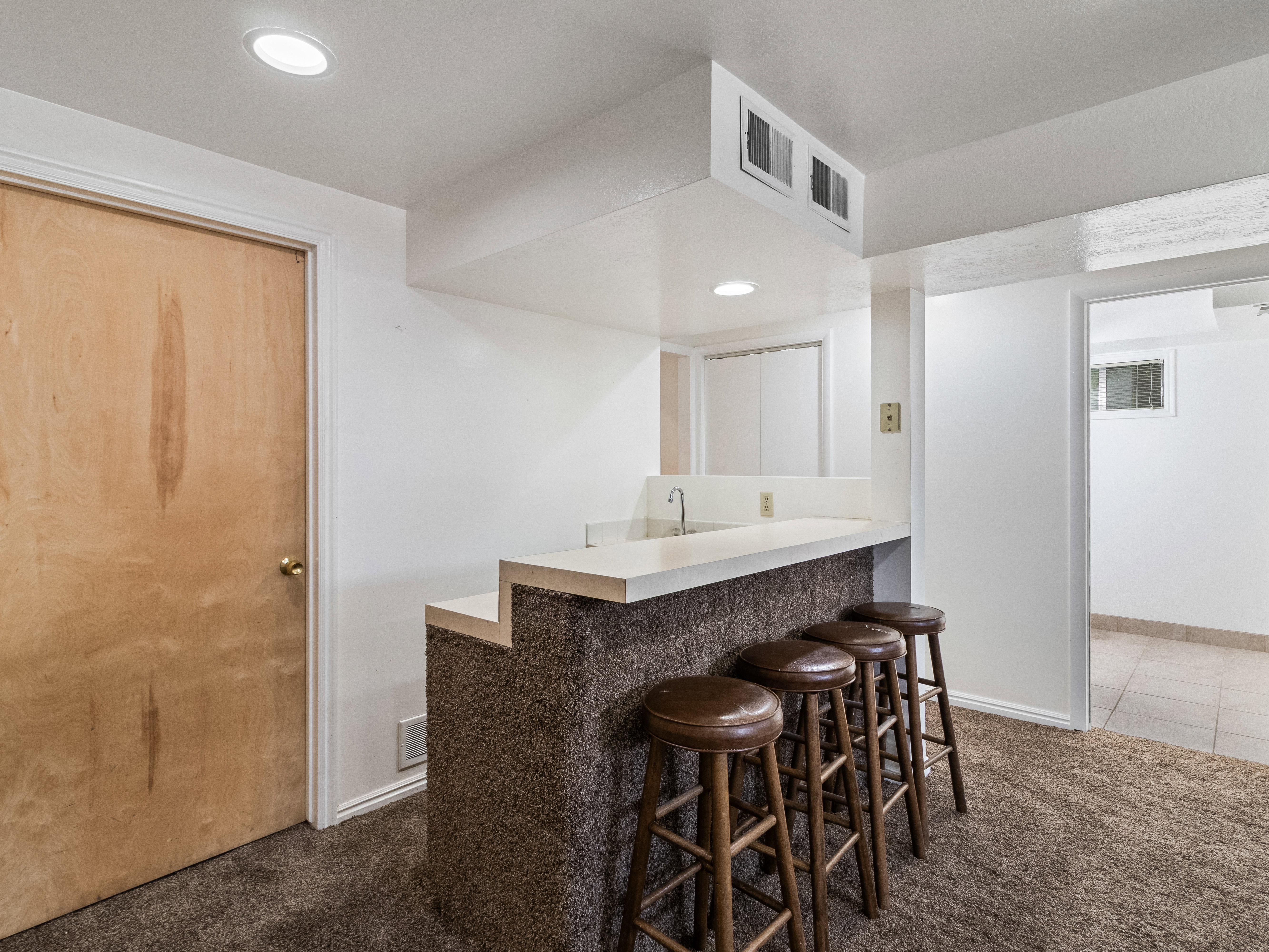Wet bar featuring a light-colored countertop, integrated sink, and recessed lighting