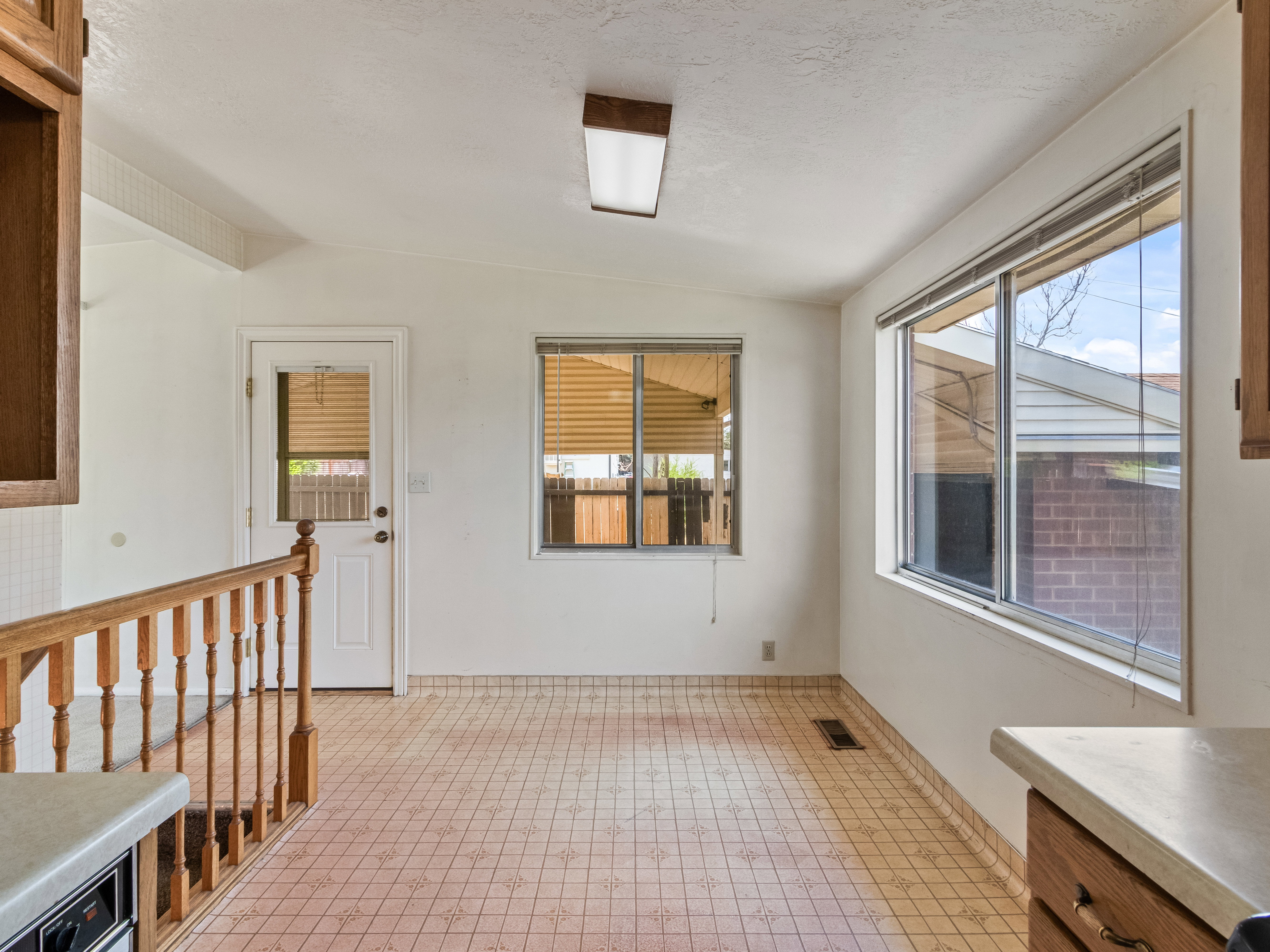 Open room featuring patterned tile flooring, a white back entry door, and multiple windows providing natural light